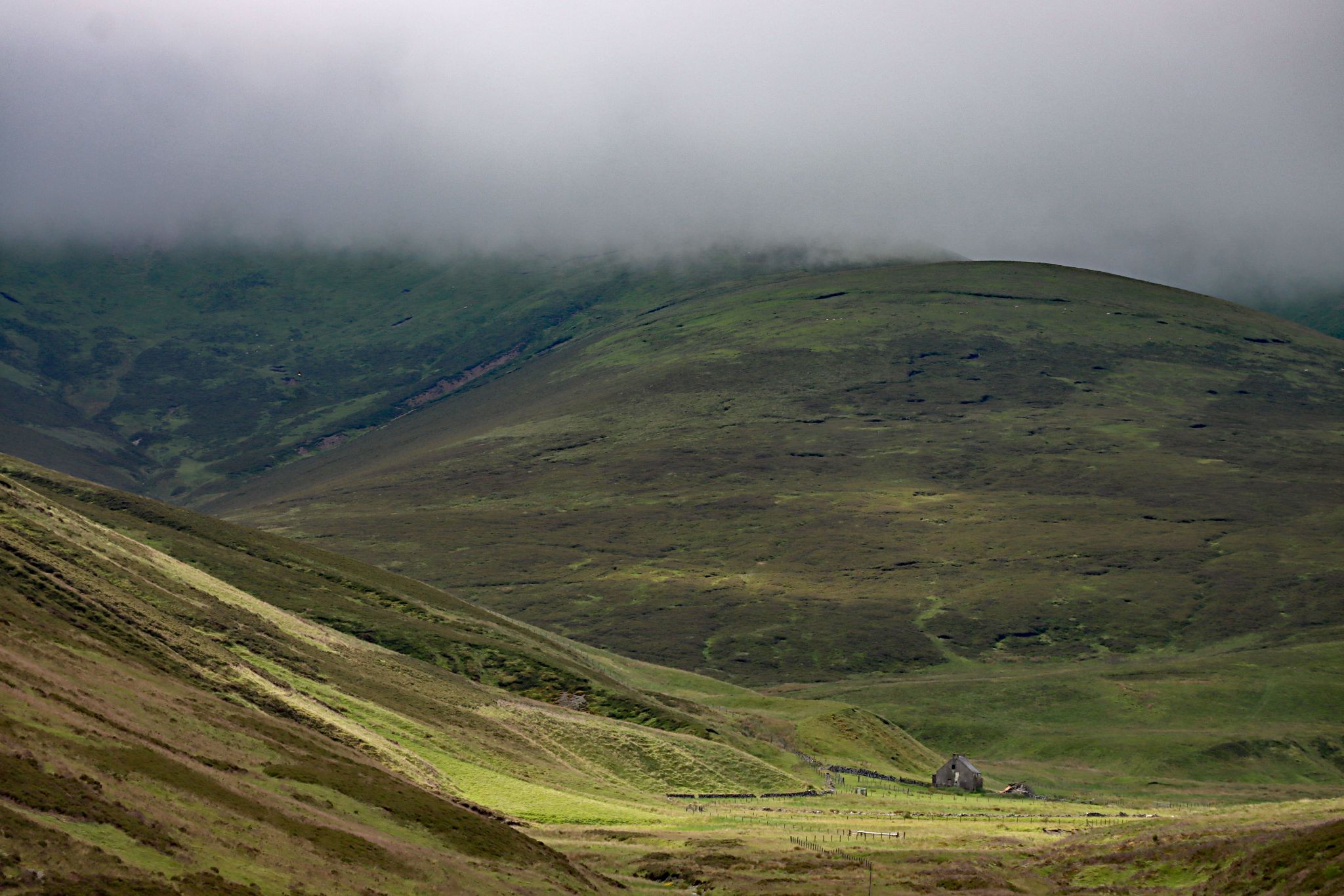 panoramic view of vast green valley with barn in the center