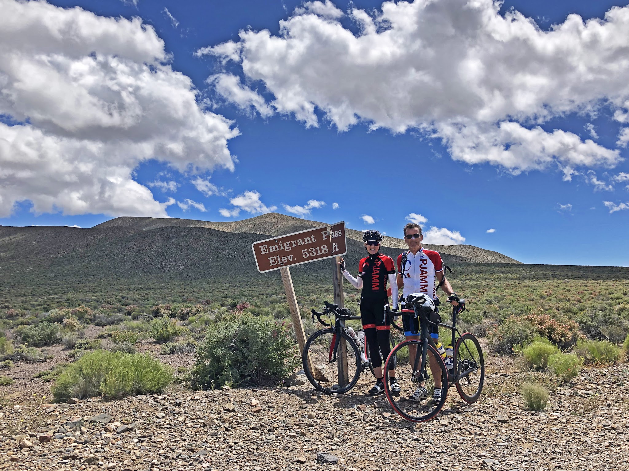Emigrant Pass, Death Valley National Park Cycling Emigrant Pass, Death Valley National Park - 2 cyclists with bikes next to summit sign
