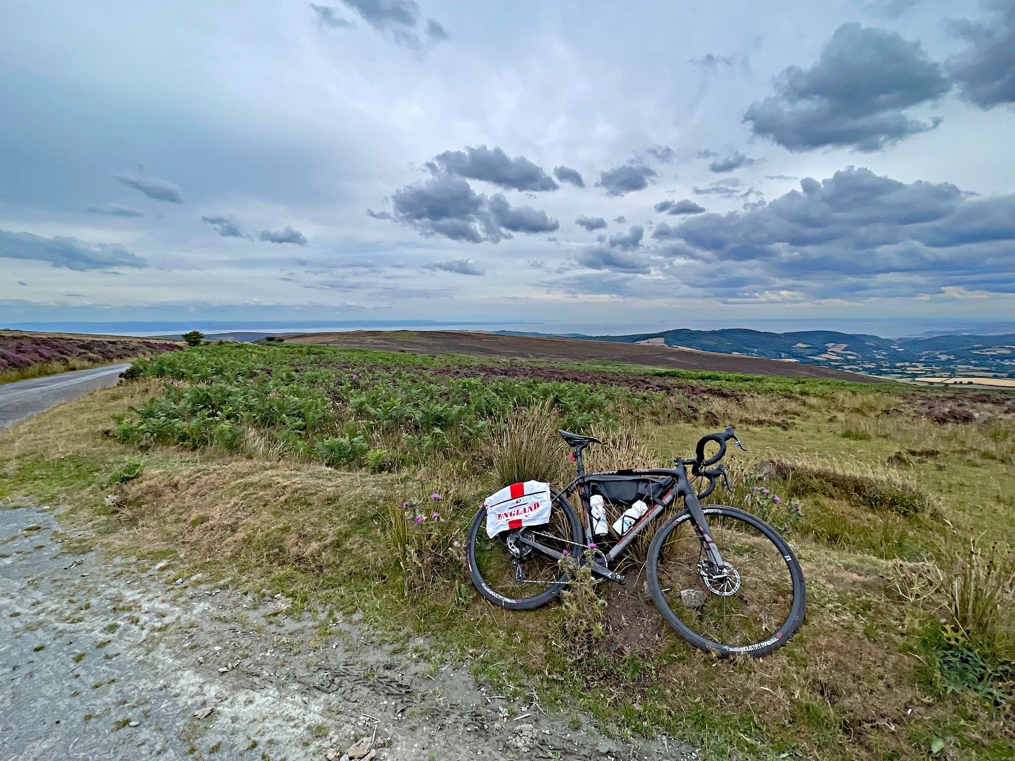 bike parked in grass on roadside at climb's finish, looking down over Bristol Channel