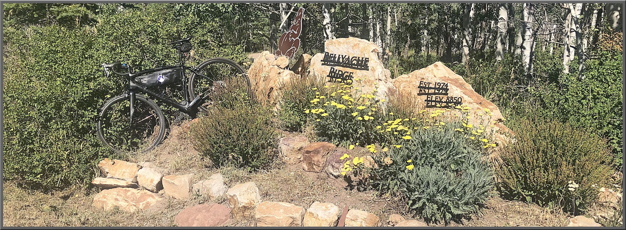 Cycling Bellyache Ridge, Colorado - bike parked in brush next to stone sign for Bellyache Ridge