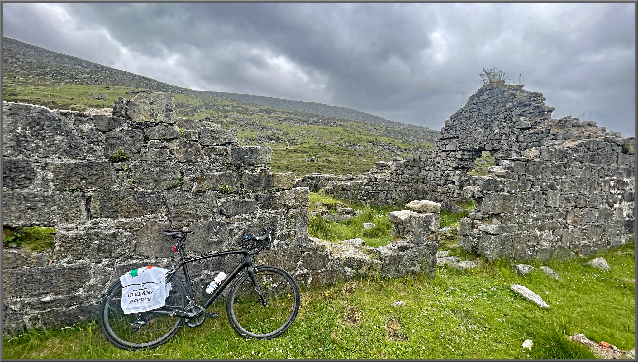 Cycling Wicklow Gap East, Ireland bike parked next to stone ruins in grassy hillside