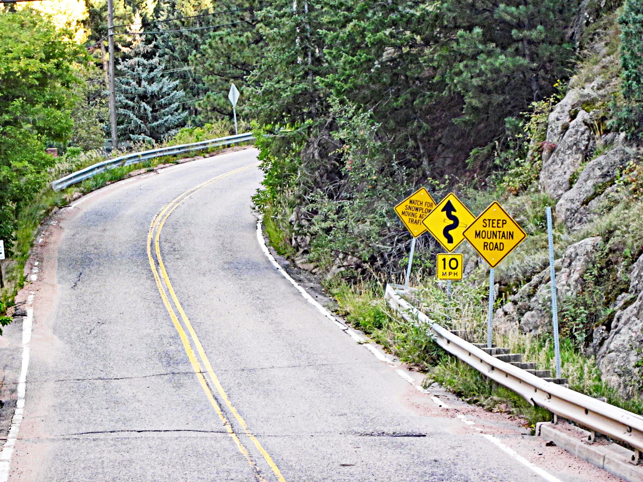 Climbing Magnolia Drive, Boulder, Colorado - stretch of two-lane roadway curving up mountainside, road signs warning of Steep Mountain Road and windy road, 10 MPH road sign