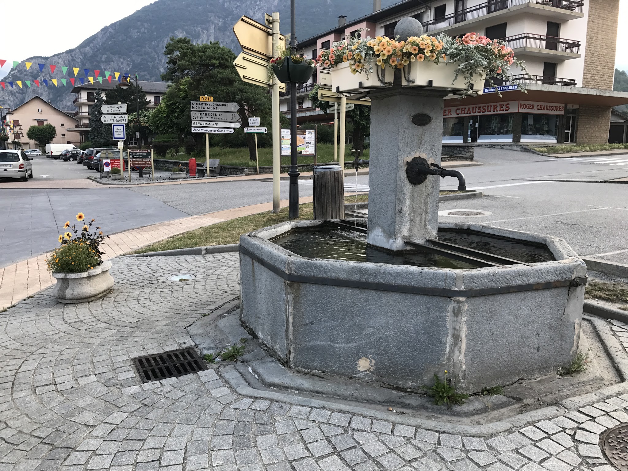 Bike climb of Col de Madeleine from La Chambre  - water fountain and road sign in town square