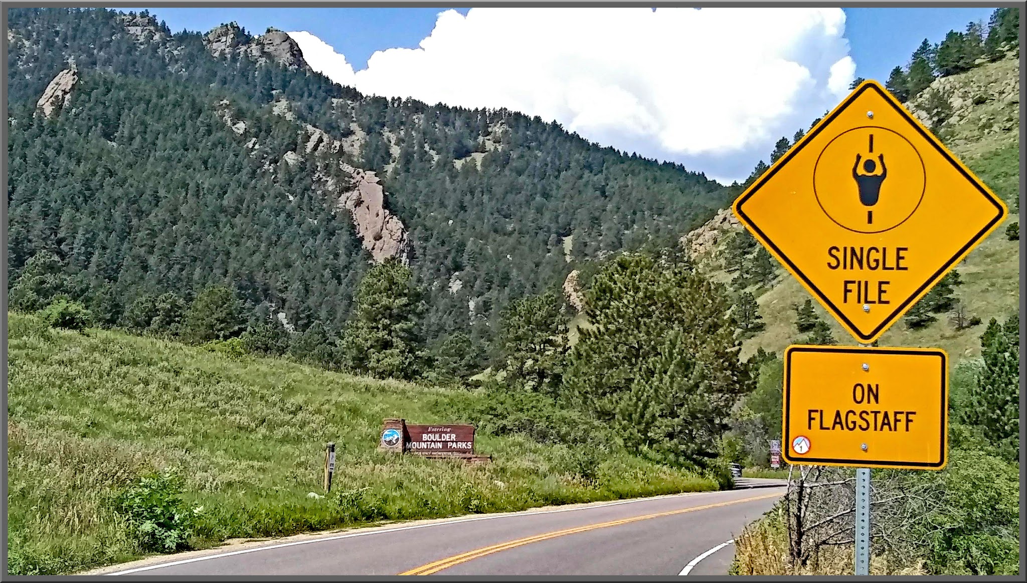 Cycling Super Duper Flag, Boulder, Colorado - two-lane road surrounded by evergreen covered hillsides, road sign reminding cyclists to ride Single File on Flagstaff, wooden sign for Boulder Mountain Parks