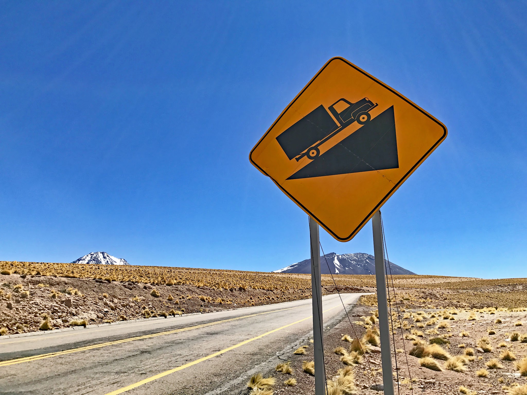 Bicycling climb Hwy 27, Atacama, Chile - steep grade sign, volcano, roadway