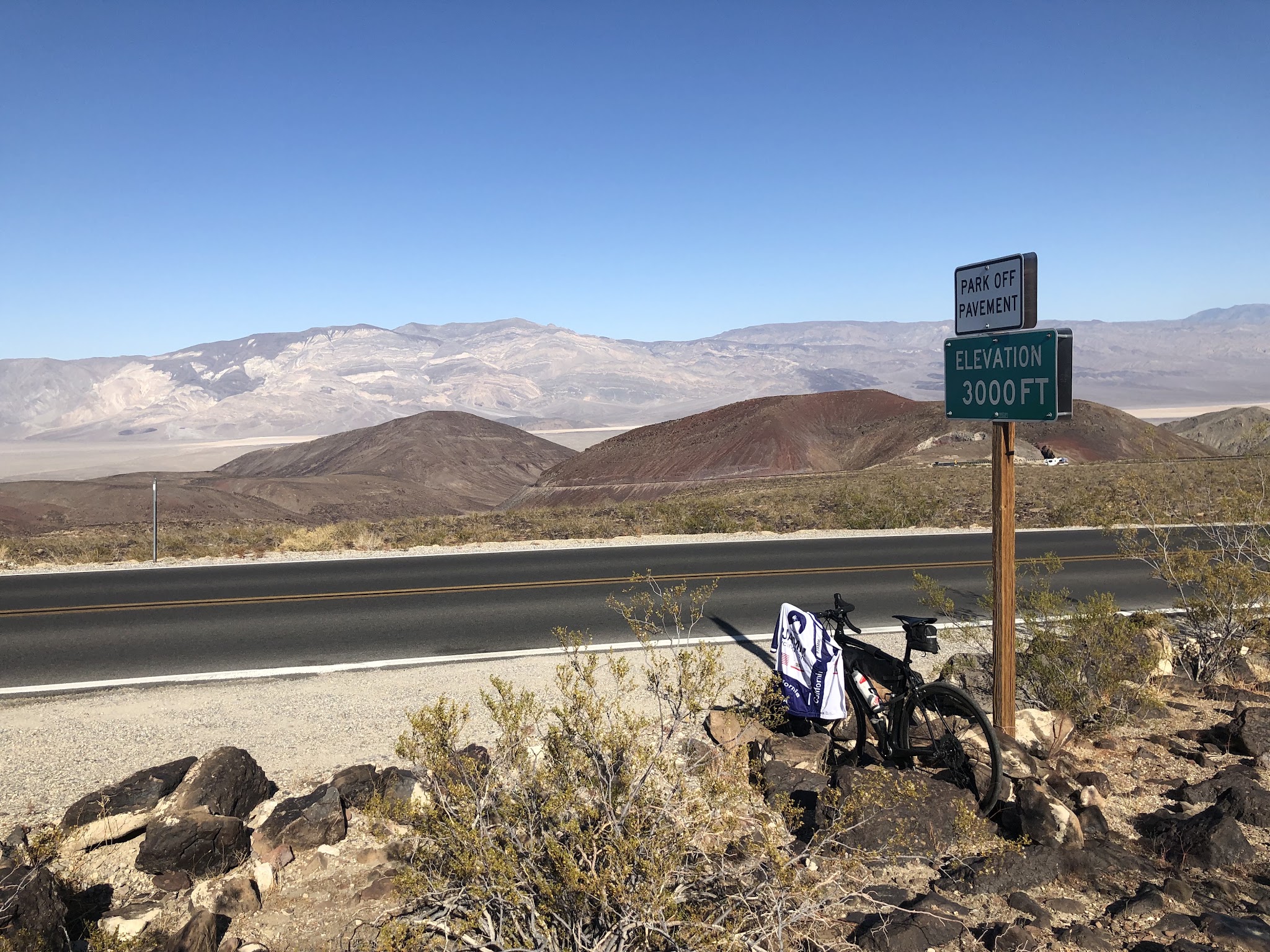 Climbing by bike Panamint Grade - bike with pjamm jacket leaning against 3000 foot sign