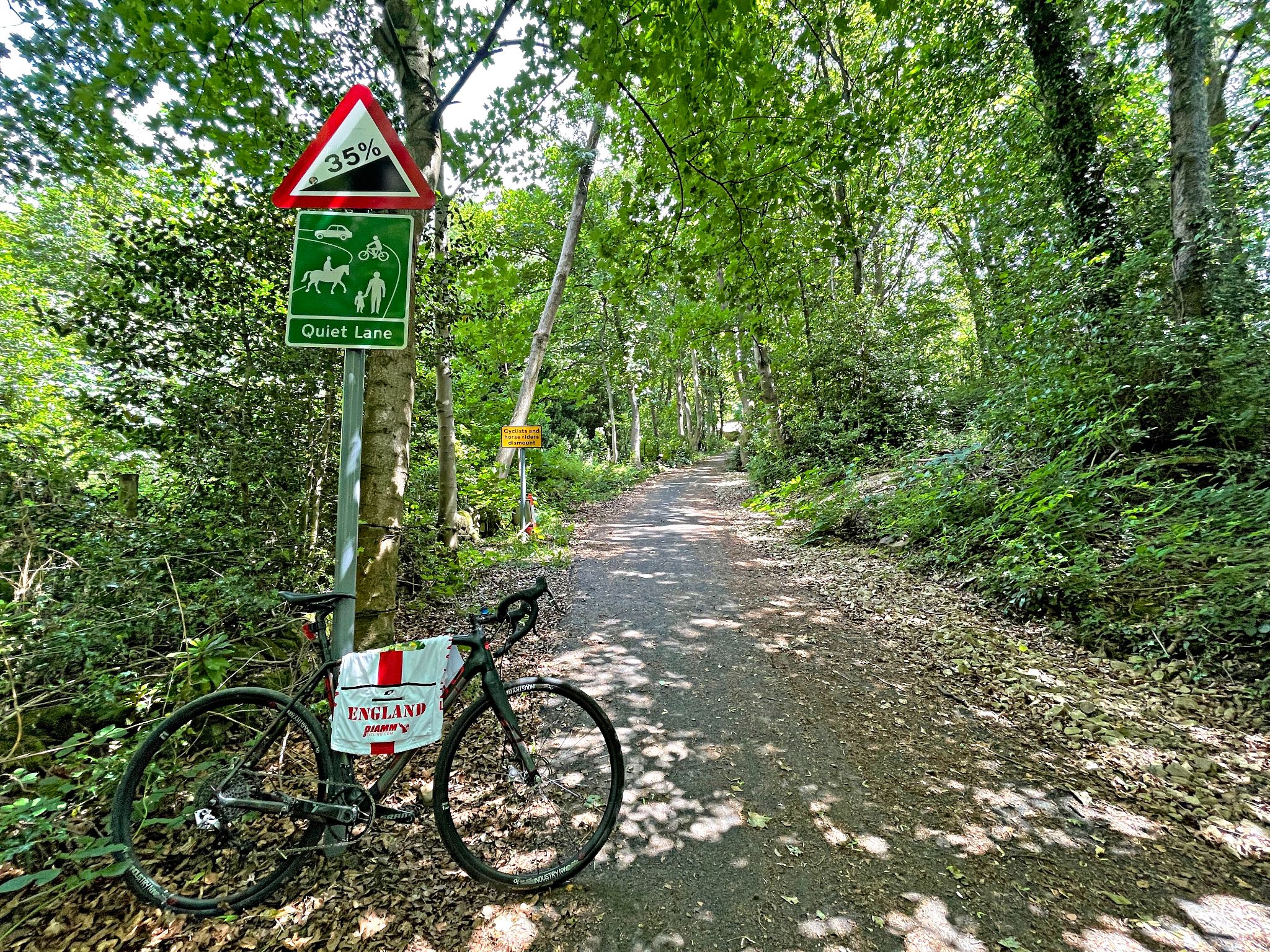 Cycling Bamford Clough bike parked next to street sign reading 35% grade and Quiet Lane