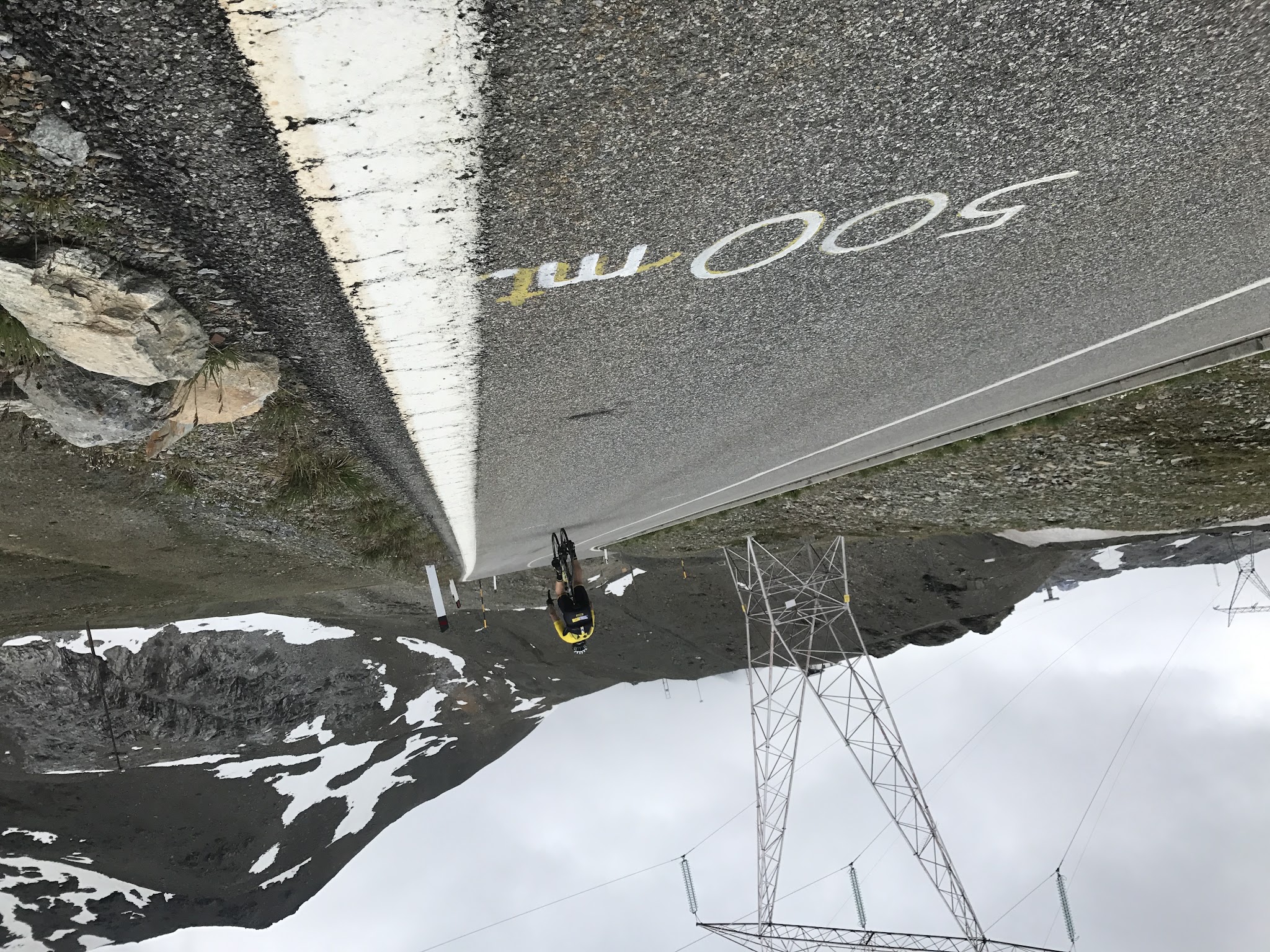 Riding bike to Umbrail Pass and Stelvio - 500 m mark painted on road, cyclist