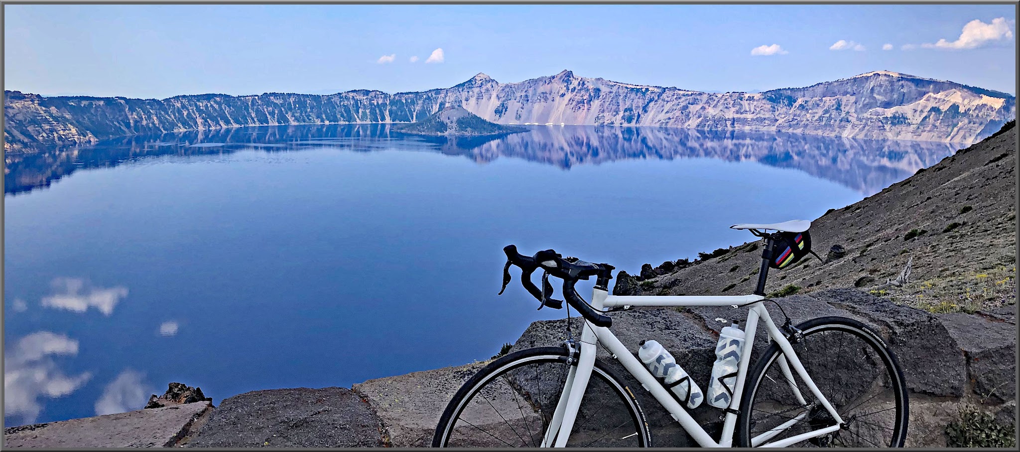 Cycling Crater Lake, Oregon, Northern Entrance - bike parked along low stone retaining wall overlooking deep blue caldera of Crater Lake