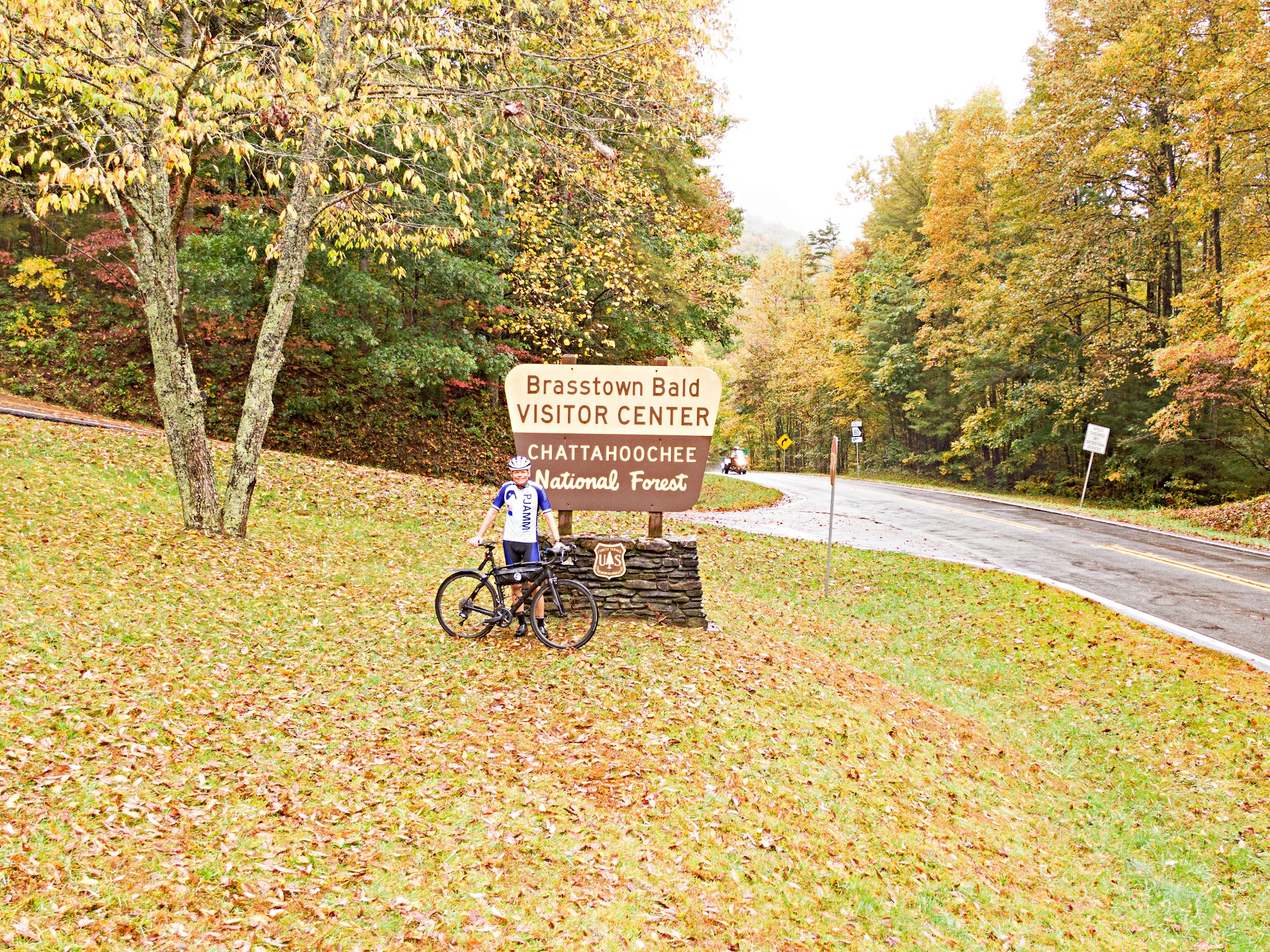 PJAMM Cyclist stands with bike in front of NPS sign for Brasstown Bald Visitor Center
