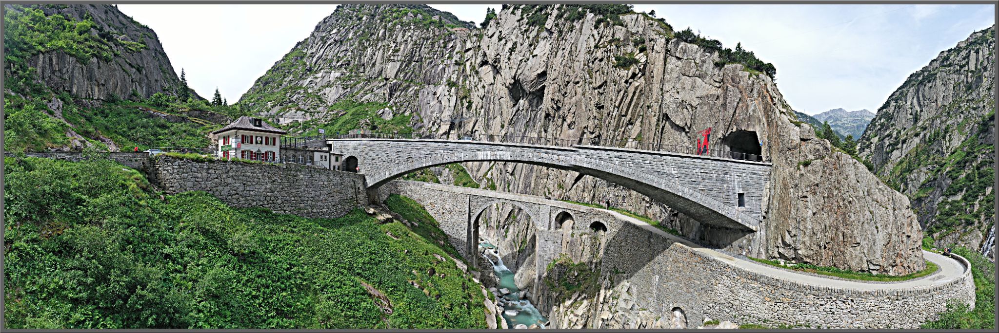 photo shows Devil's Bridge - stone bridge crossing over roadway and river below, heading into tunnel in mountainside