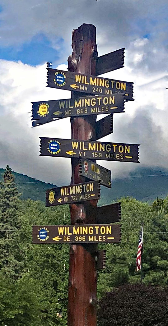 Cycling Whiteface Mountain - tall wooden post with 10 different Wilmington signs, notating how far Wilmington is from various other cities