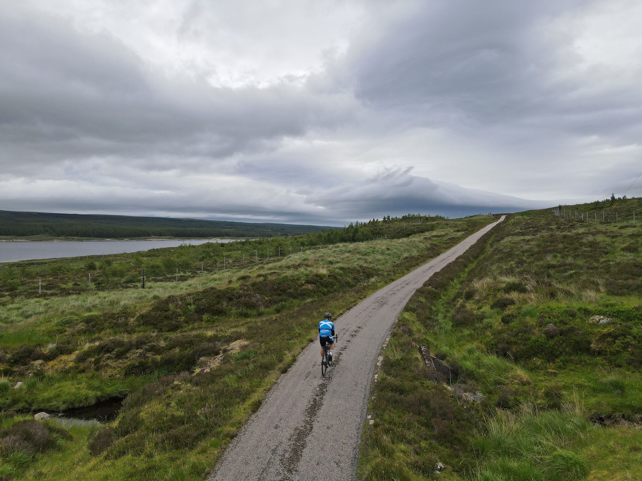 PJAMM cyclist rides bike near starting point; roadway runs along Loch Shin