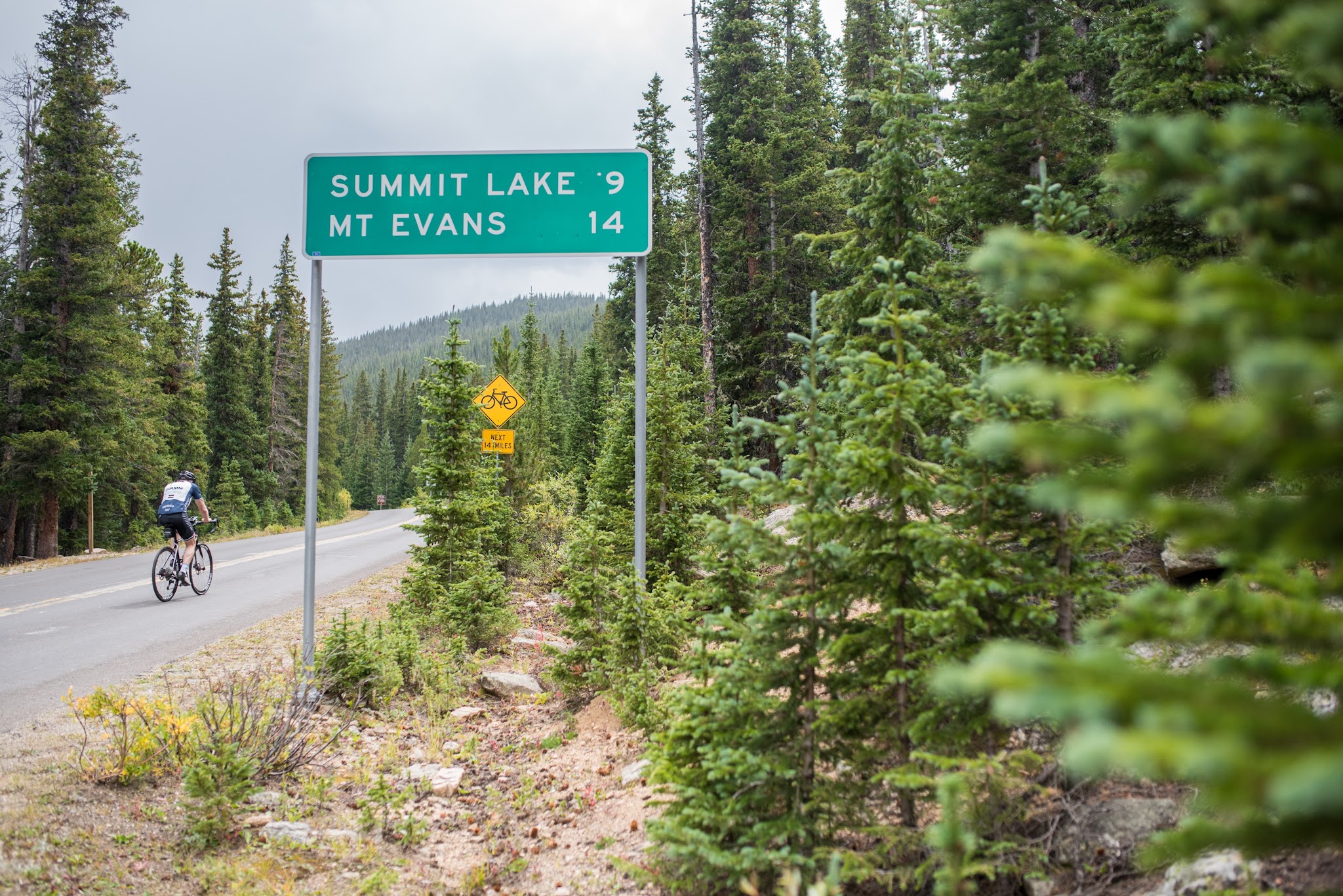 Cycling past road sign on Mt Evans Road Rocky Mountains
