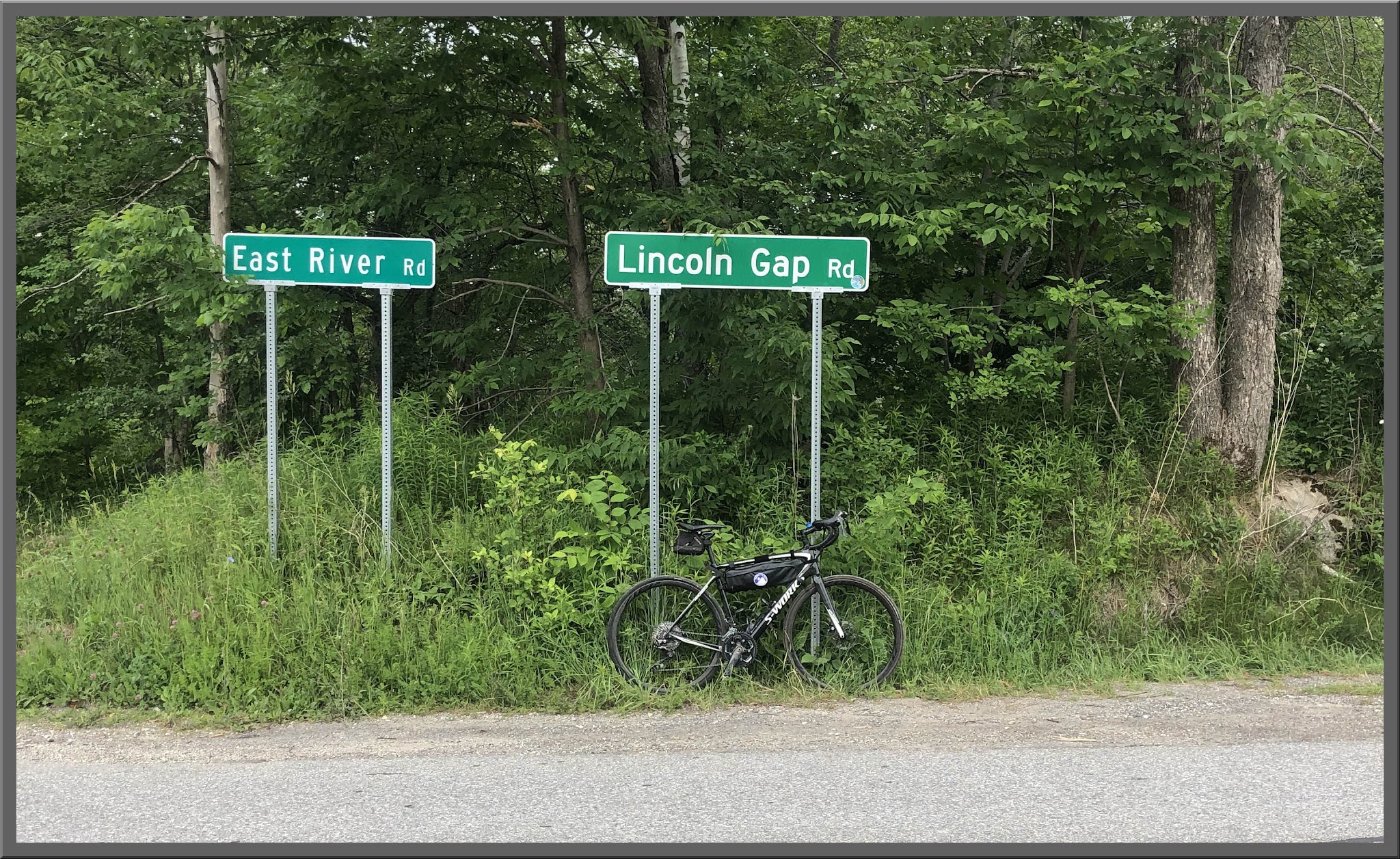 Lincoln Gap West Cycling Lincoln Gap West - Road signs for East River Road and Lincoln Gap Road, bike leaning against Lincoln Gap Road sign, dense grasses and foliage behind signs, road in foreground