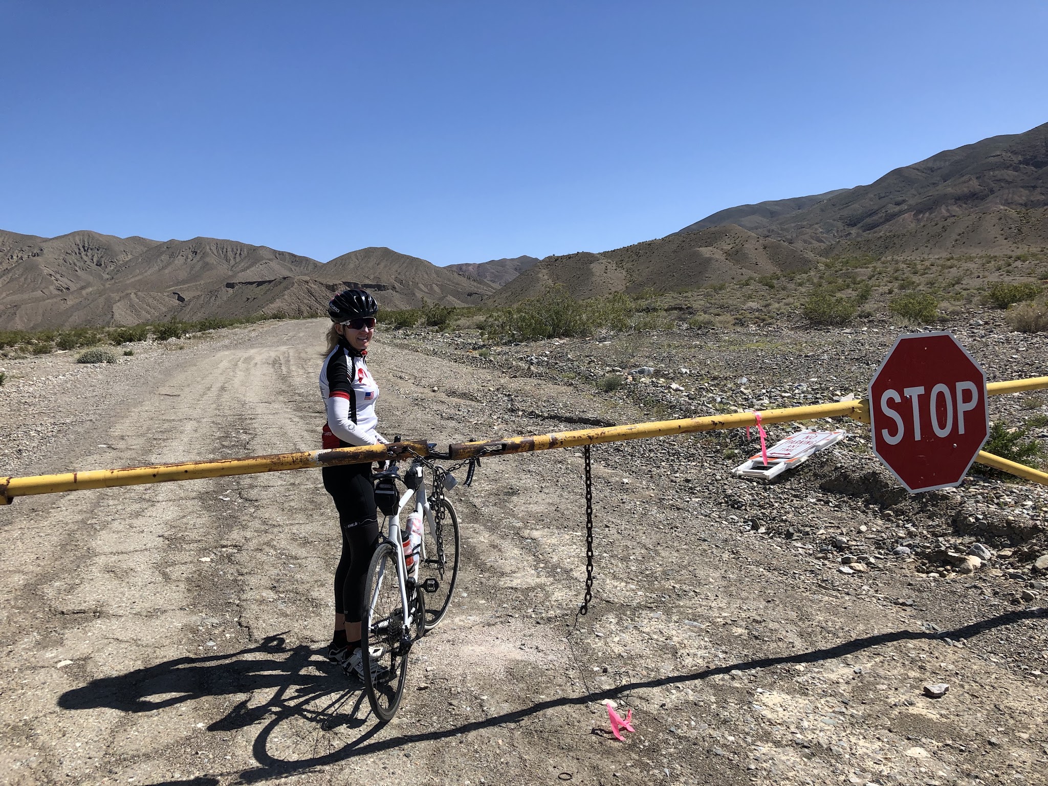Cycling Death Valley National Park, California Cycling Death Valley National Park, California - cyclist stands with bike beyond closed gate at Wildrose