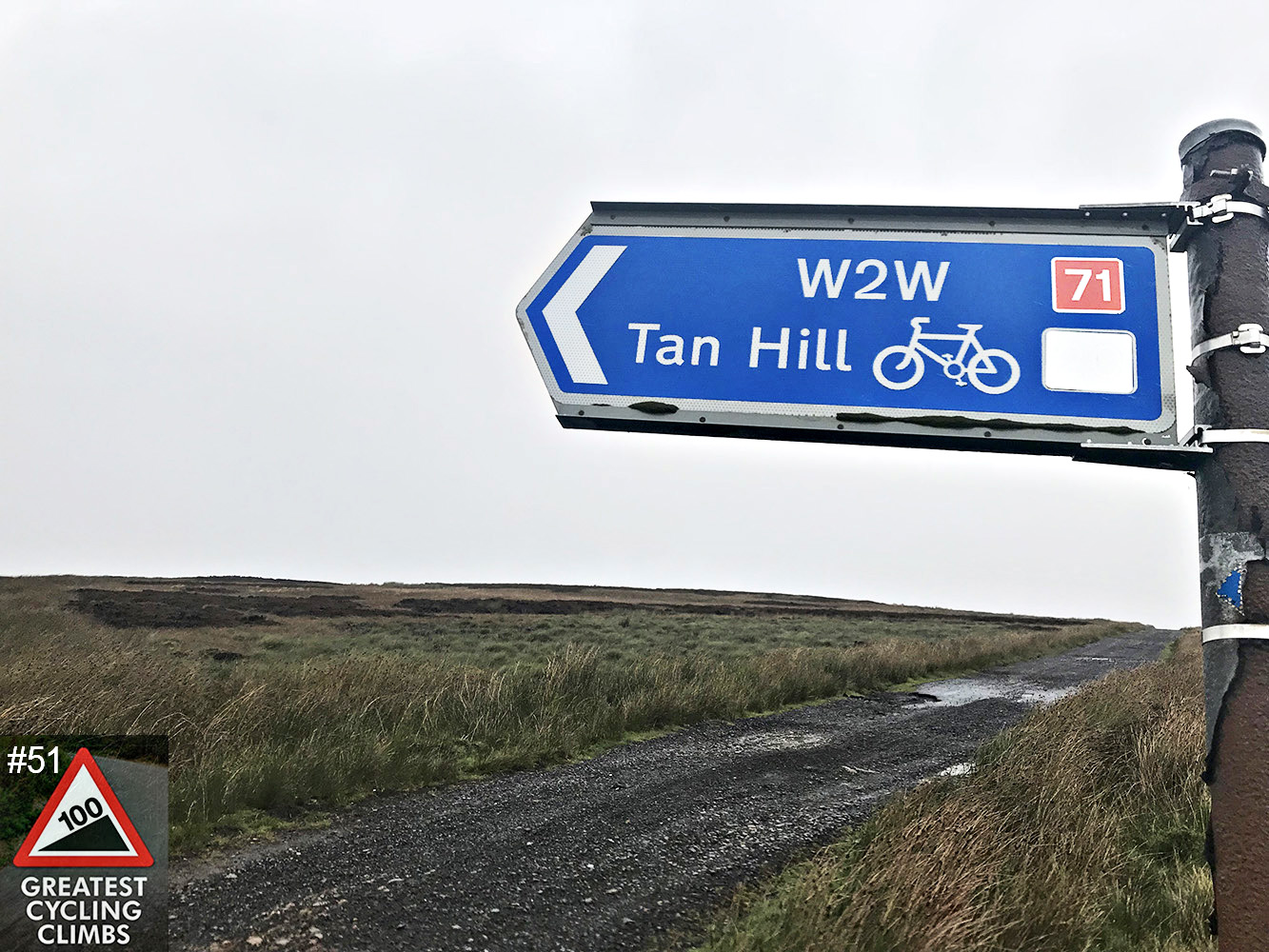 Cycling Tan Hill, UK - Simon Warren's 100 Greatest Cycling Climbs #51 logo in corner, road sign along narrow dirt road for W2W Tan Hill