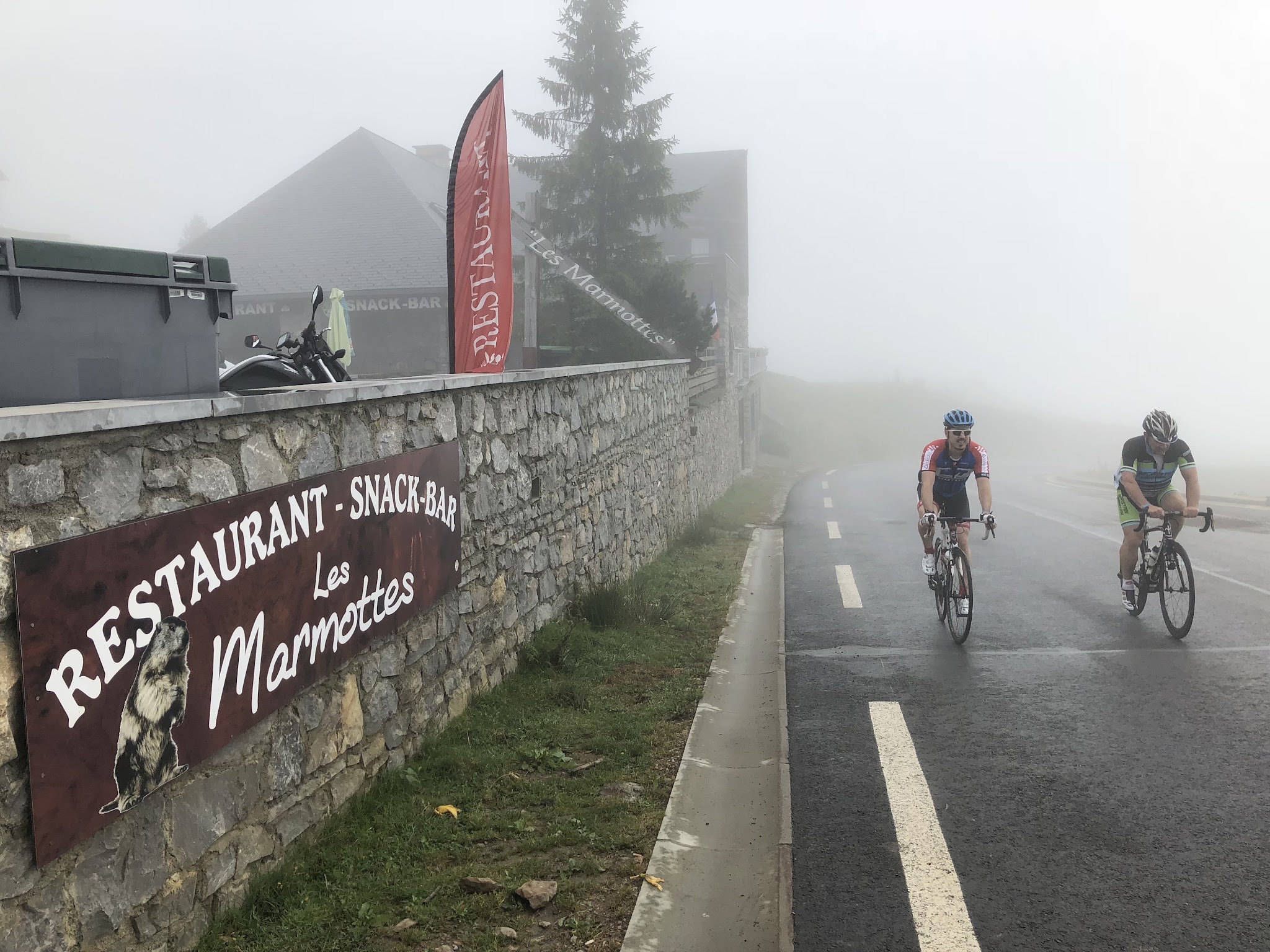 Bicycling Col du Soulor from Arrens - col sign at the top with cyclists riding by