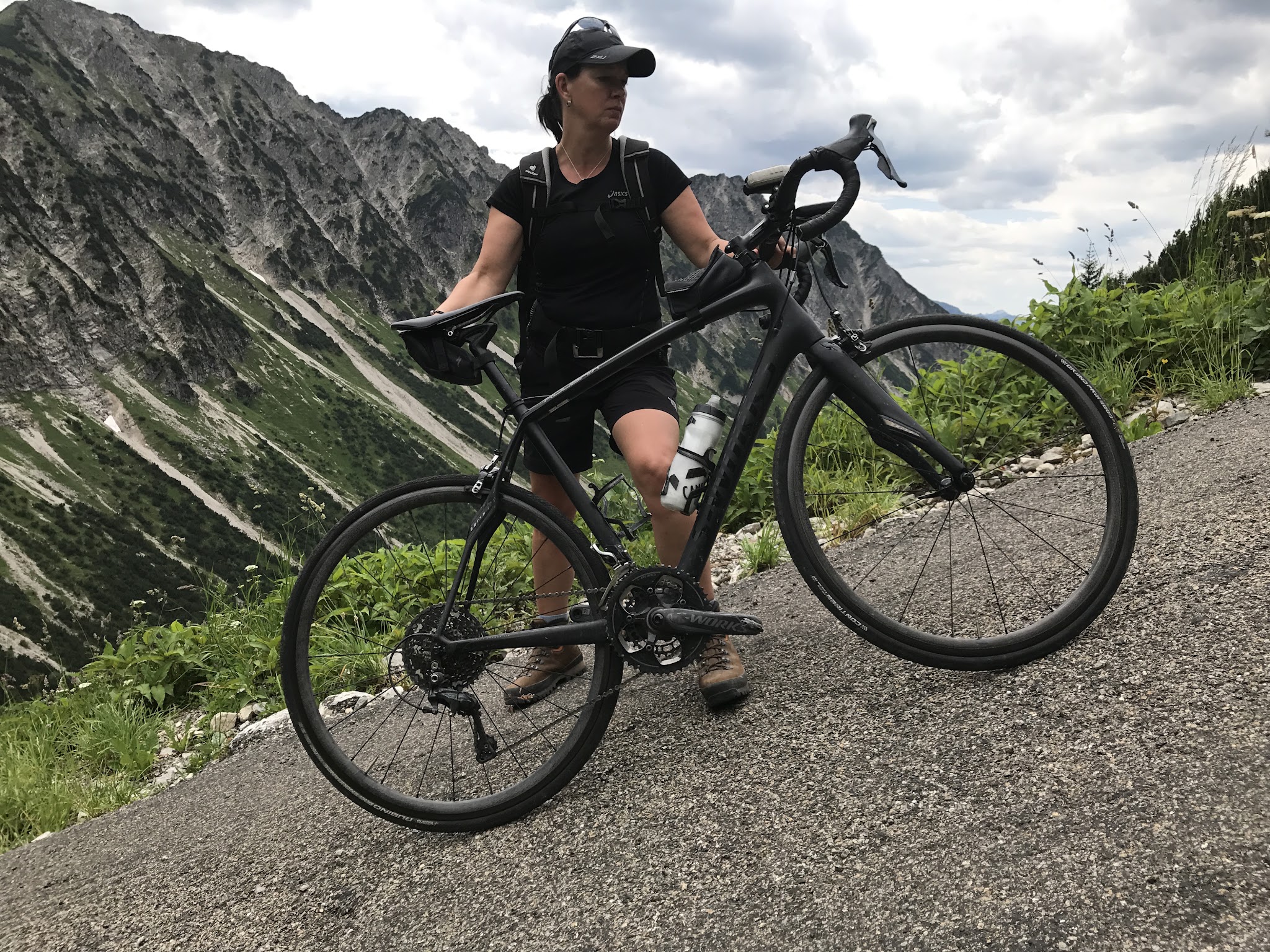 Bicycle climb of Nebelhorn - hiker holding bike on steep road