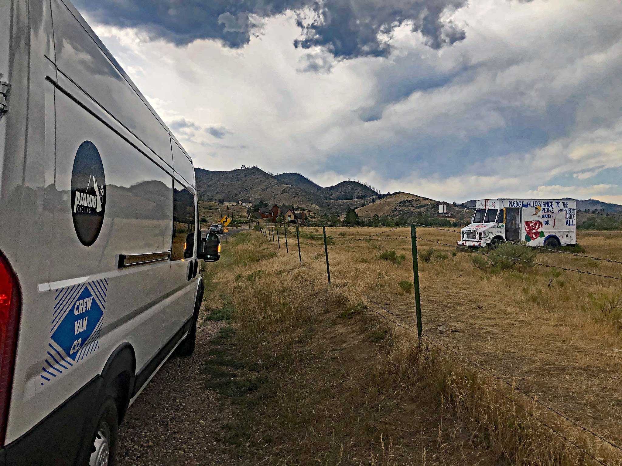 Cycling Rist Canyon East - PJAMM Cycling's white SAG van parked on roadside near old graffitied abandoned milk truck in field