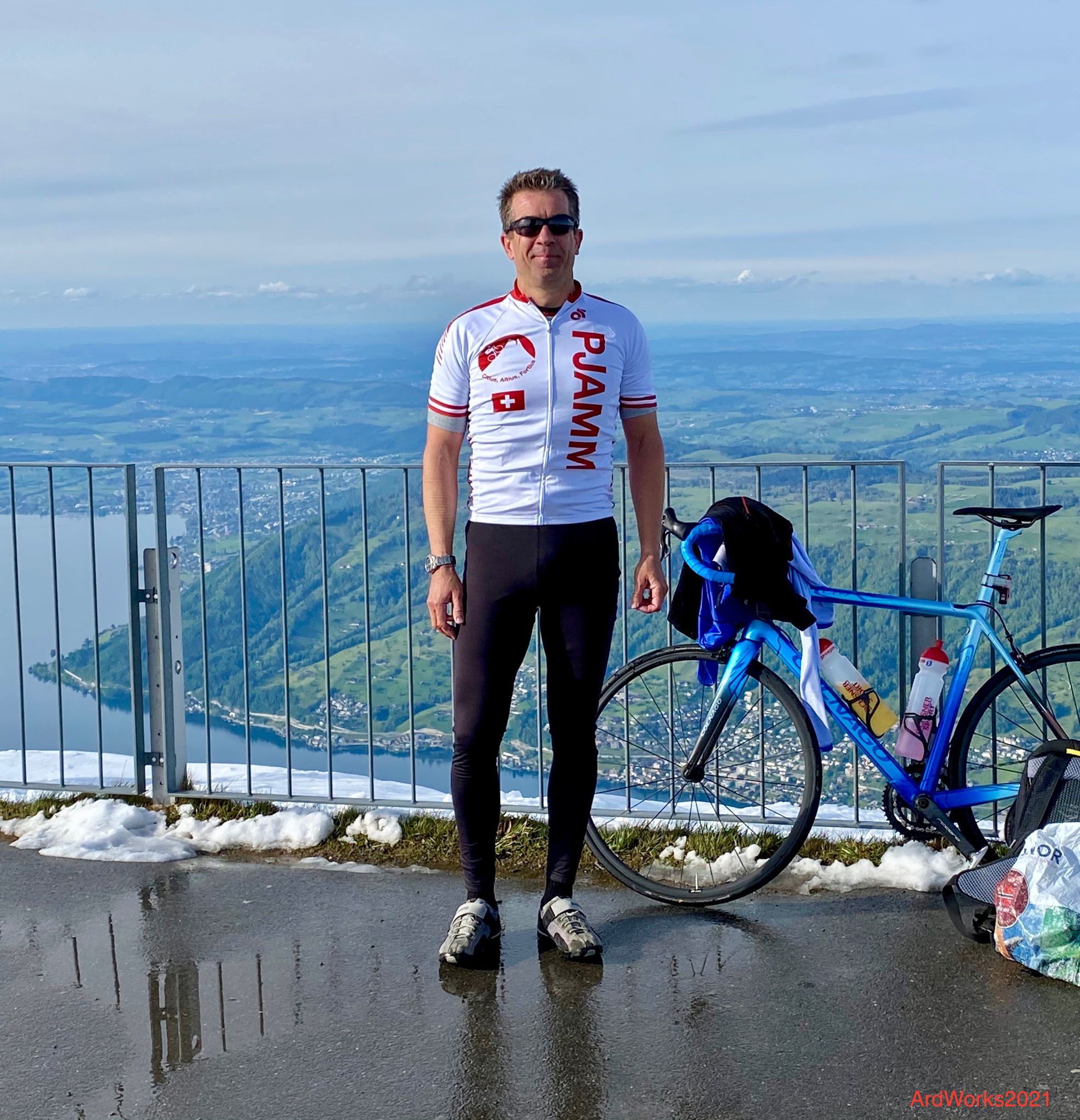 Cycling Mount Rigi, Switzerland - PJAMM Cyclist Aard Oostra stands with bike on top of Mt. Rigi, snow in background, lake below
