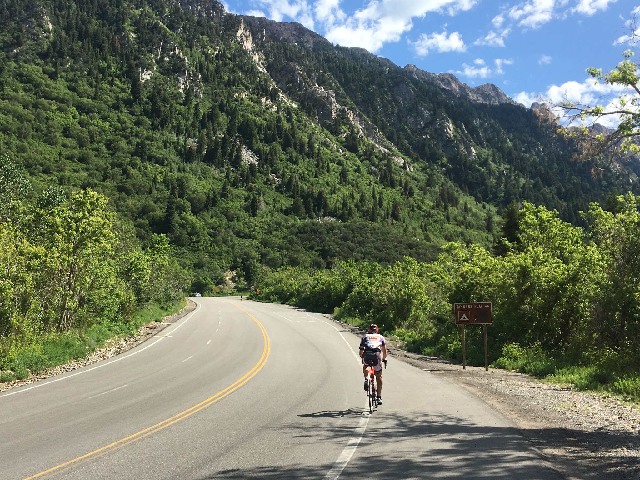 Cyclist with bike at top of Little Cottonwood Canyon climb by bike.