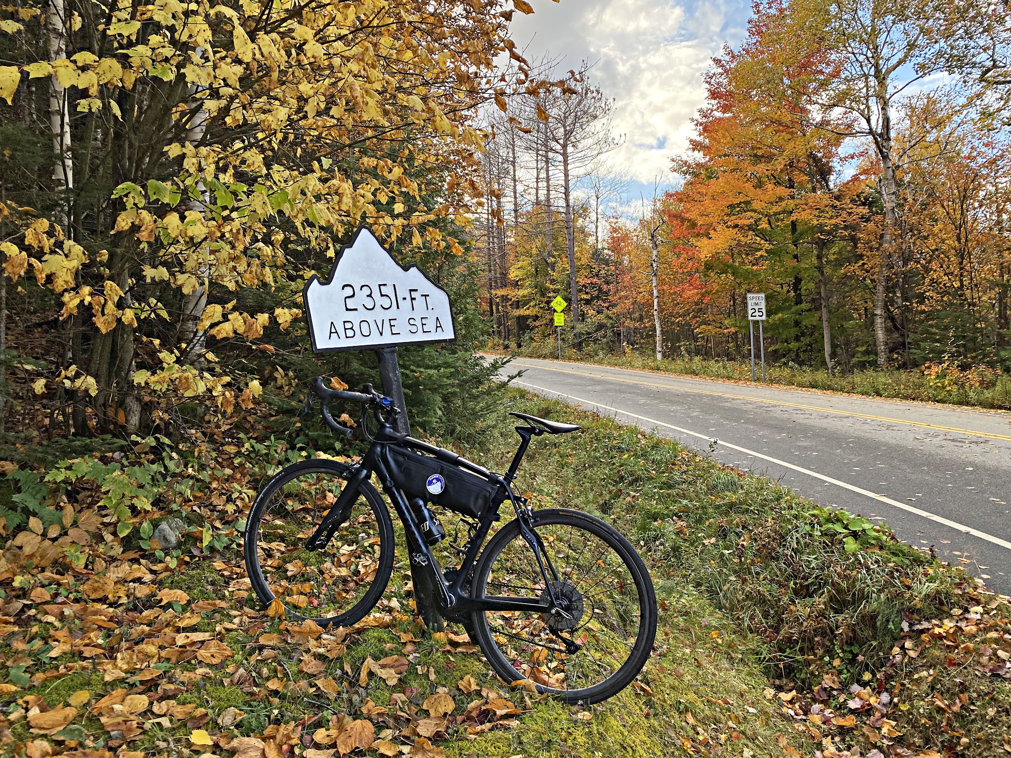Cycling Whiteface Mountain, New York - bike parked along roadside next to white mountain shaped elevation marker sign, fall foliage