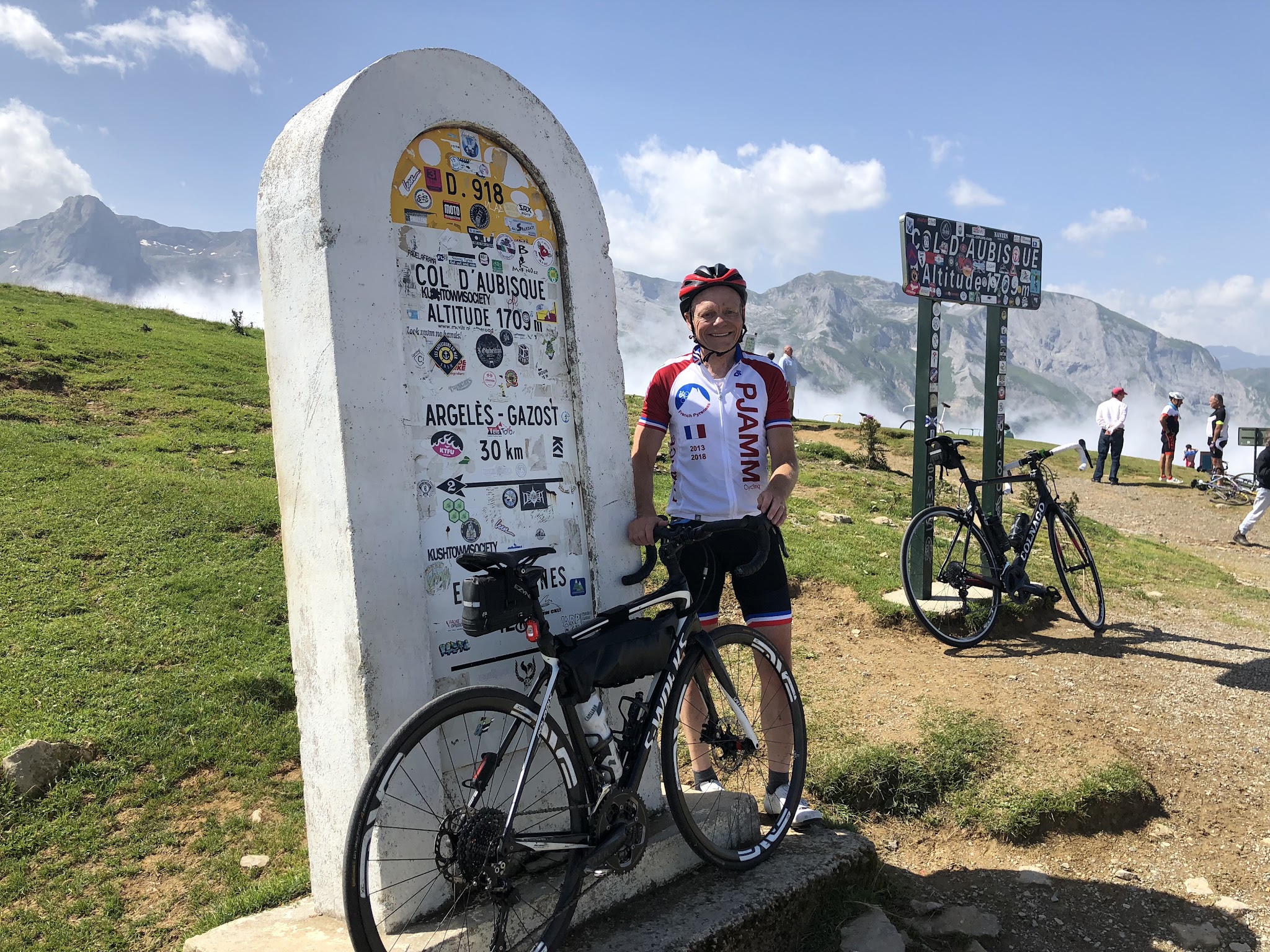 Cycling Col d'Aubisque - cyclist at col sign with bike - John Johnson, PJAMM cycling