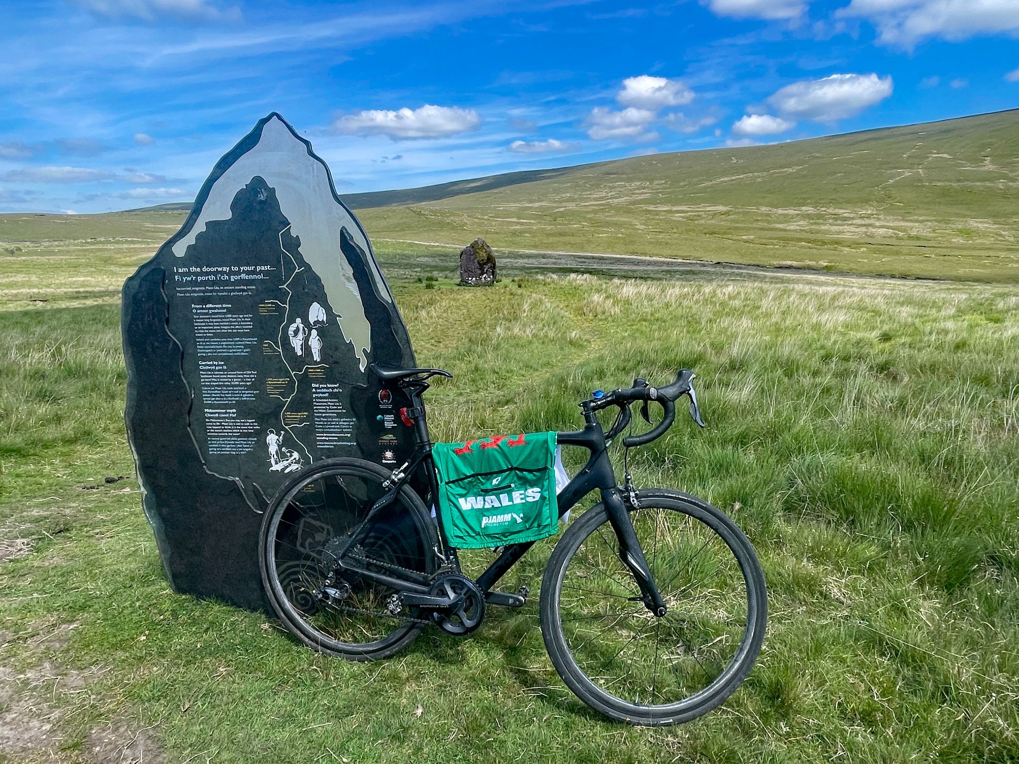 bike parked next to a monument with information about Maen Llia stone; actual stone can be seen in background