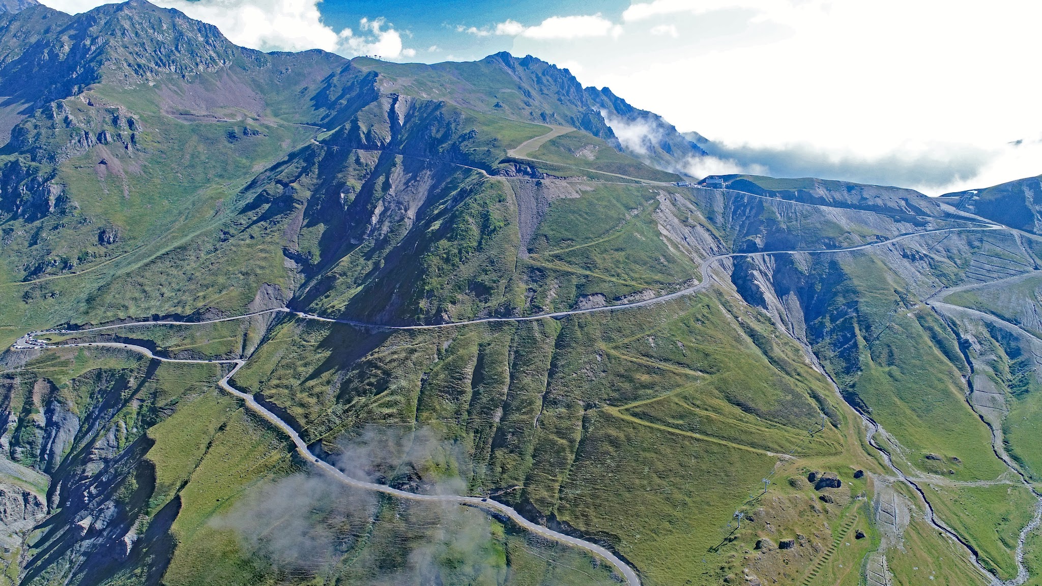 Climbing Col du Tourmalet by bike - drone aerial photo of col - cyclists, restaurant, statue, Le Géant, col sign