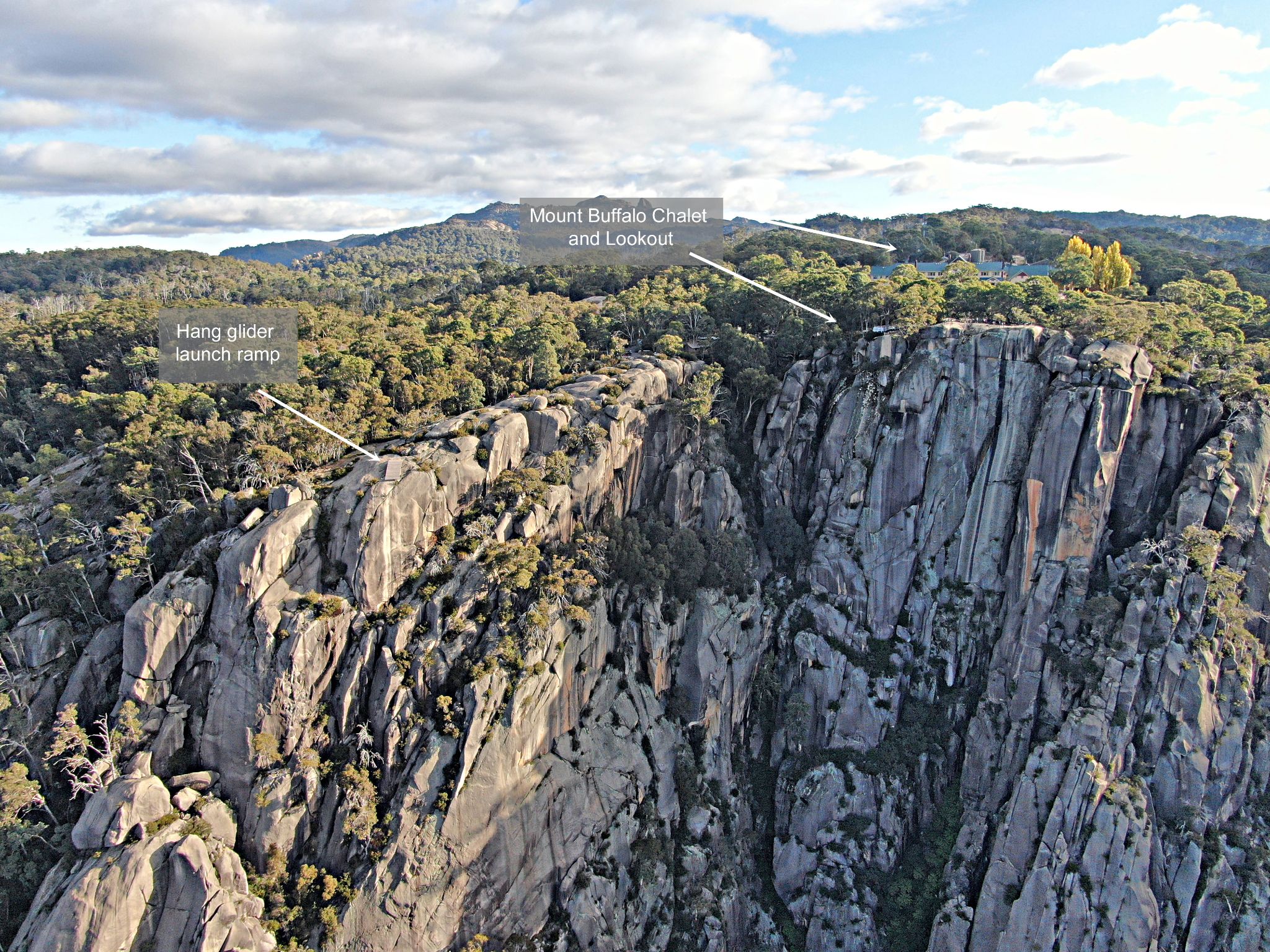 huge rock face with Mount Buffalo Chalet and lookout and hang glider launch ramp pointed out