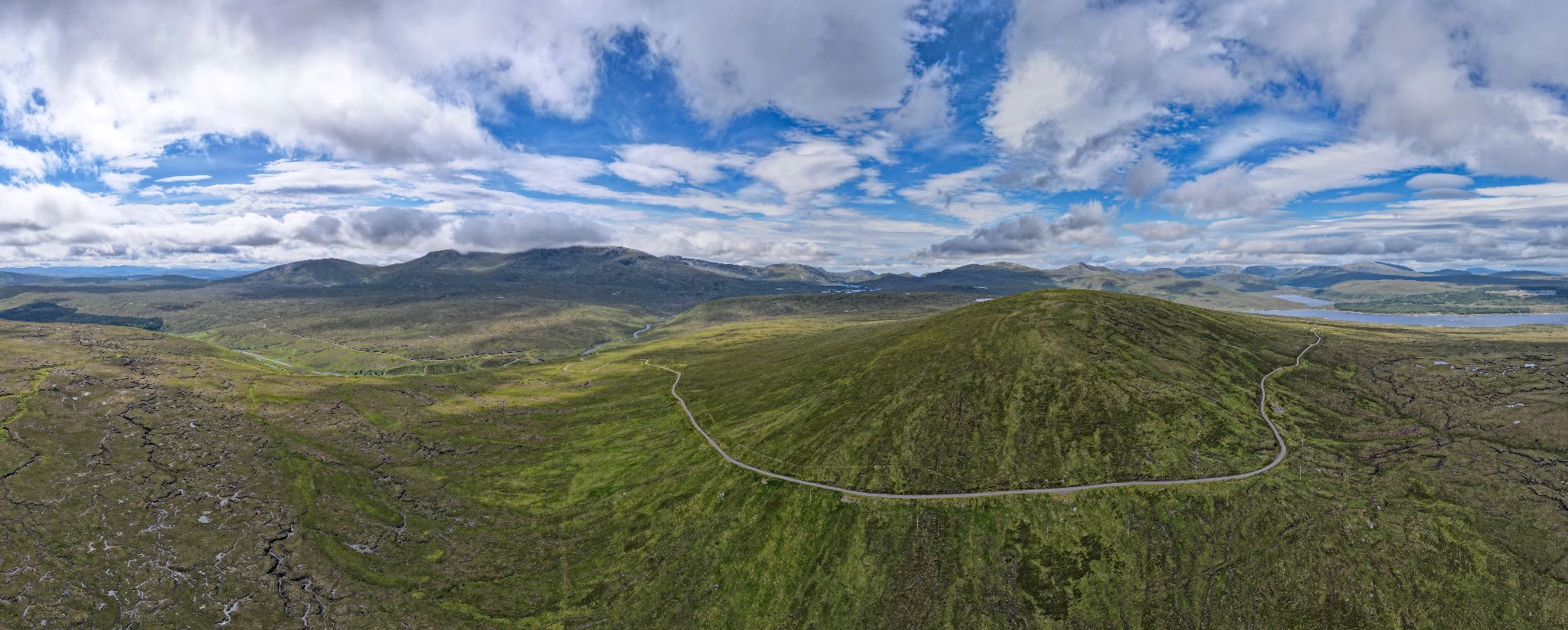 aerial view shows panoramic view of Moavally bike climb in Scotland; roadway loops around center of green mountainside