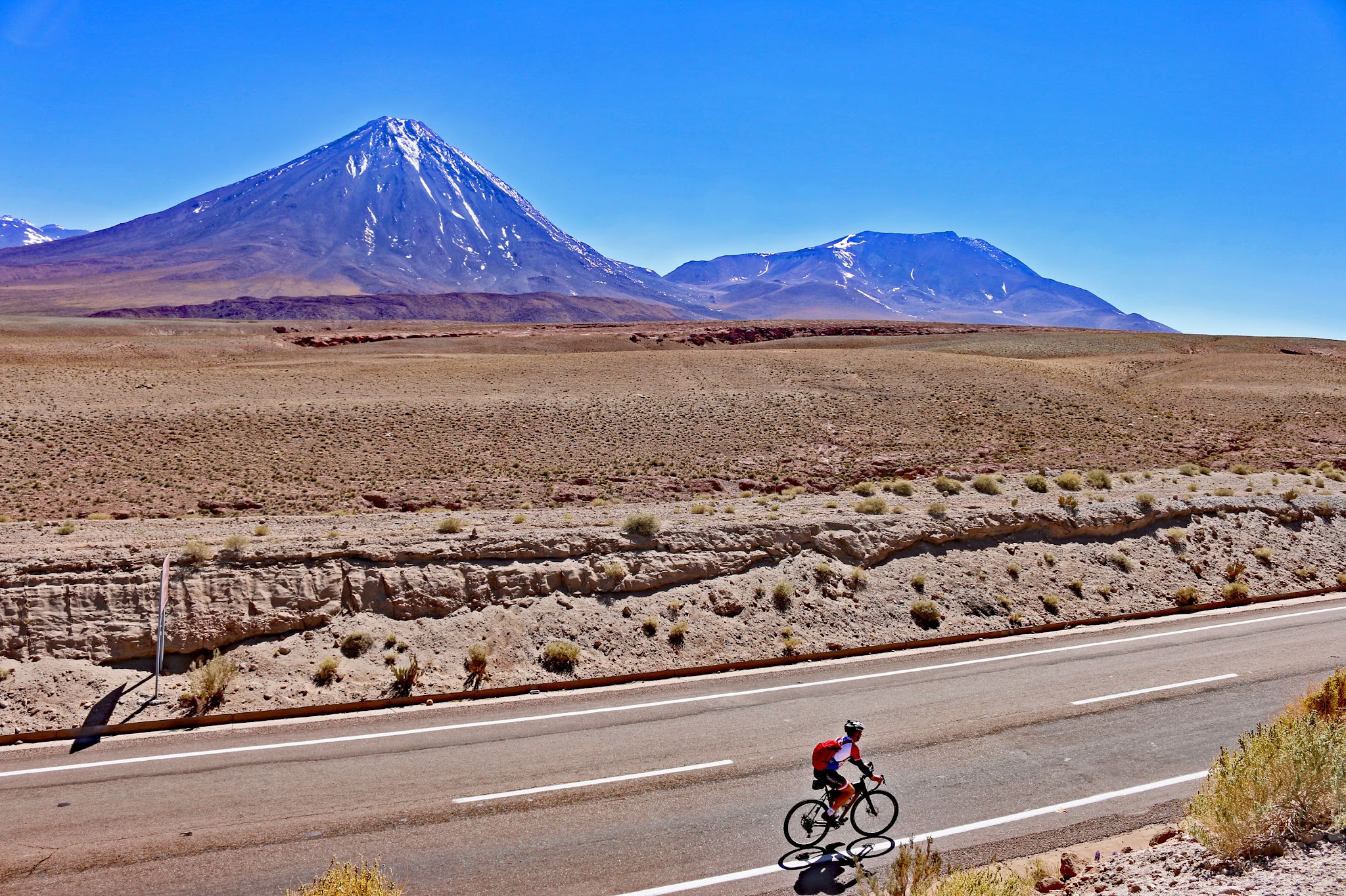 Hwy 27, Atacama, Chile Cyclist on road - volcano Licancabur in background
