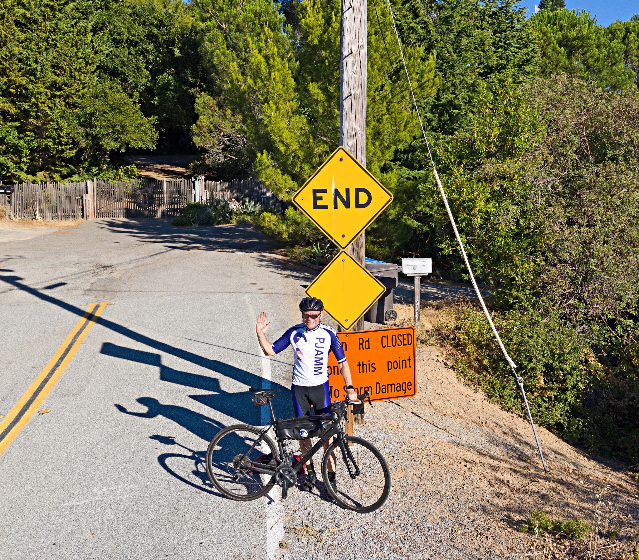 Cycling Bohlman Road, Saratoga, California - John Johnson in PJAMM Cycling jersey standing with bike and waving in front of road sign for End of road (and climb)