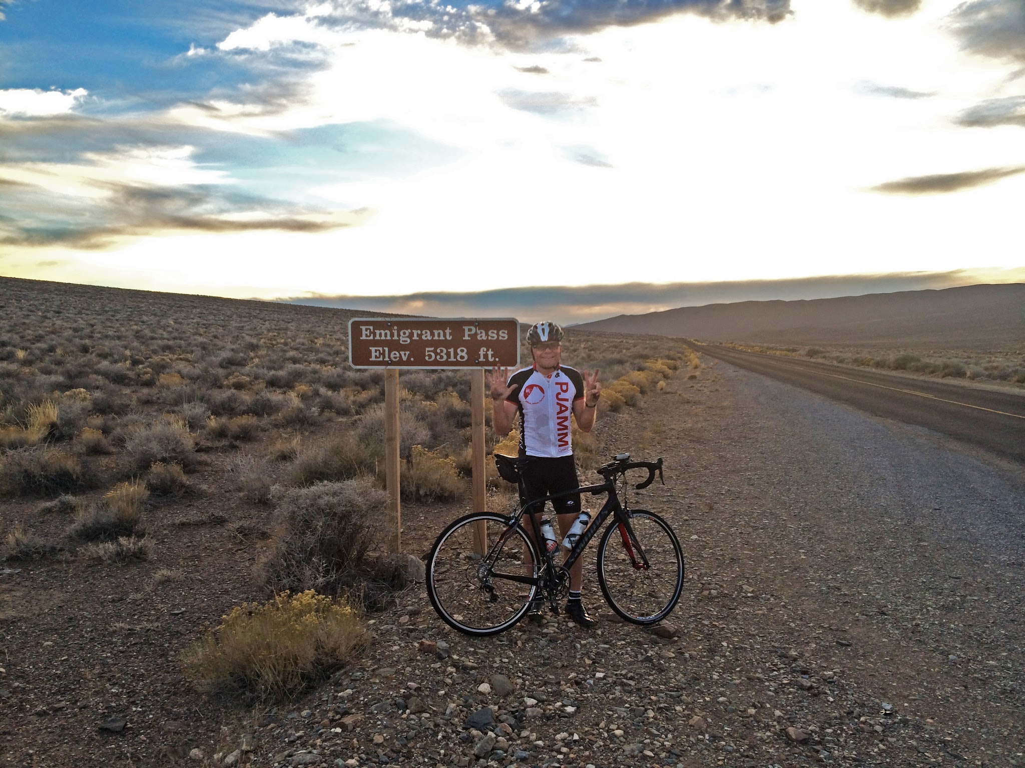 Emigrant Pass, Death Valley National Park Bicycling Emigrant Pass, Death Valley National Park - cyclist next to summit sign near road