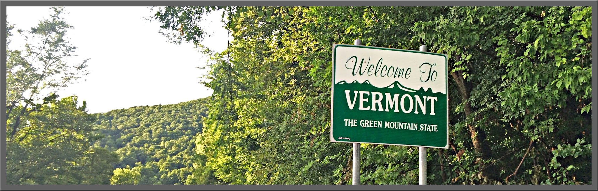 Cycling Mt. Ascutney, Vermont - road sign reads "Welcome To Vermont, the Green Mountain State", surrounded by dense green folliage