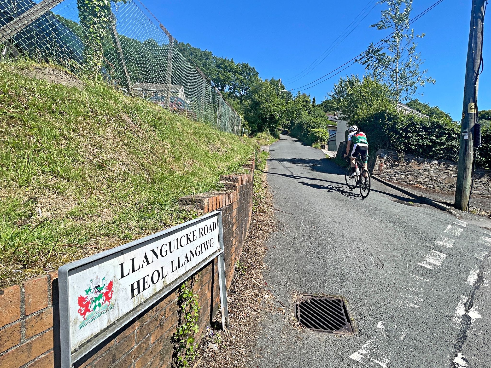 Cycling Llanguicke Road, Wales PJAMM Cyclist turns onto road in front of street sign for Llanguicke Road
