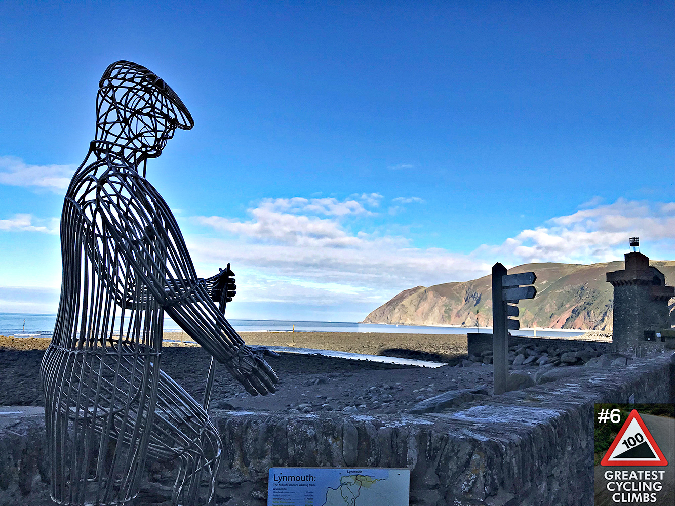 Cycling Exmoor Forest, England - Wire statue of hiking man next to stone fence, water in background, blue sky
