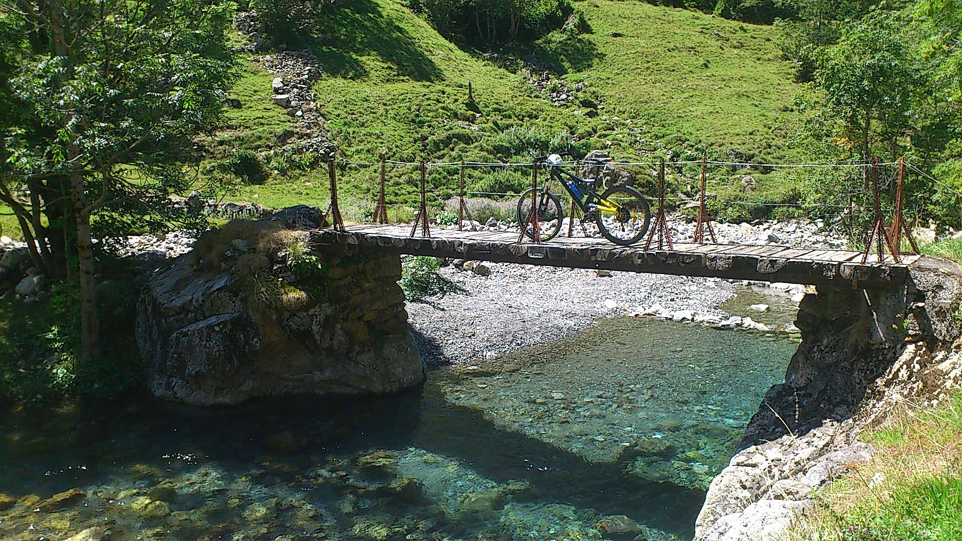 bike parked on small wooden bridge crossing over small stream with crystal blue water