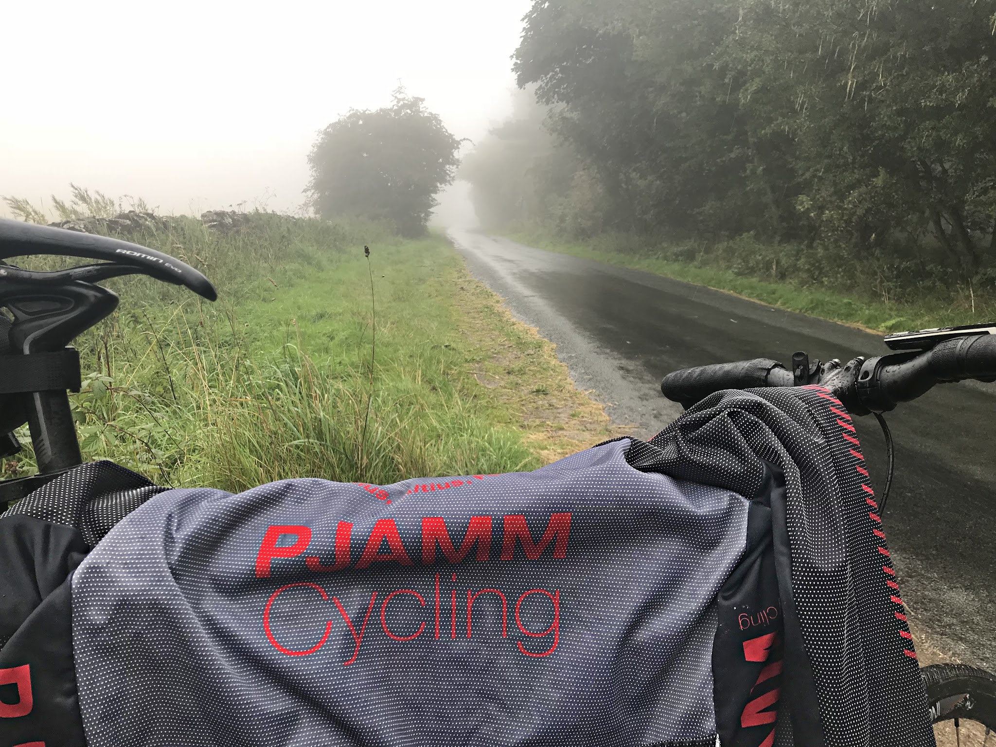 Cycling Boltby Bank, North Yorkshire, England - bike with PJAMM Cycling jersey draped over it, parked along side of wet one-lane roadway surrounded by greenery