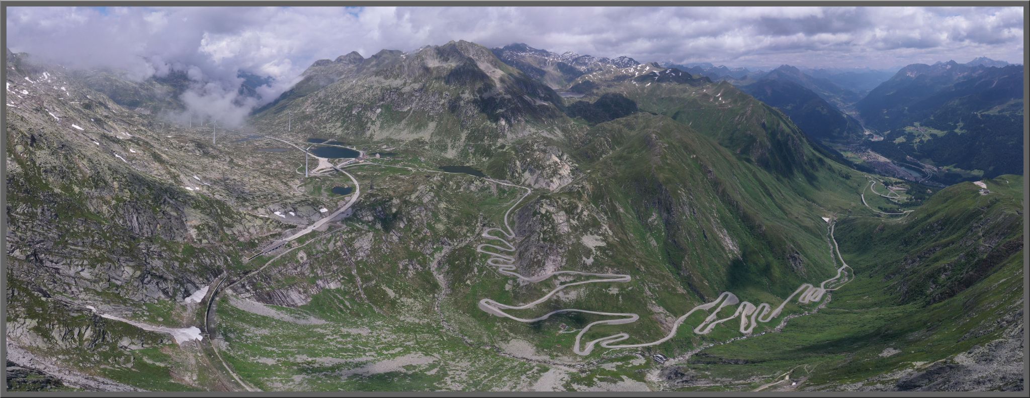 Cycling St. Gotthard Pass, Switzerland: panoramic view looking down on mountainside, with hairpins snaking their way up the climb route
