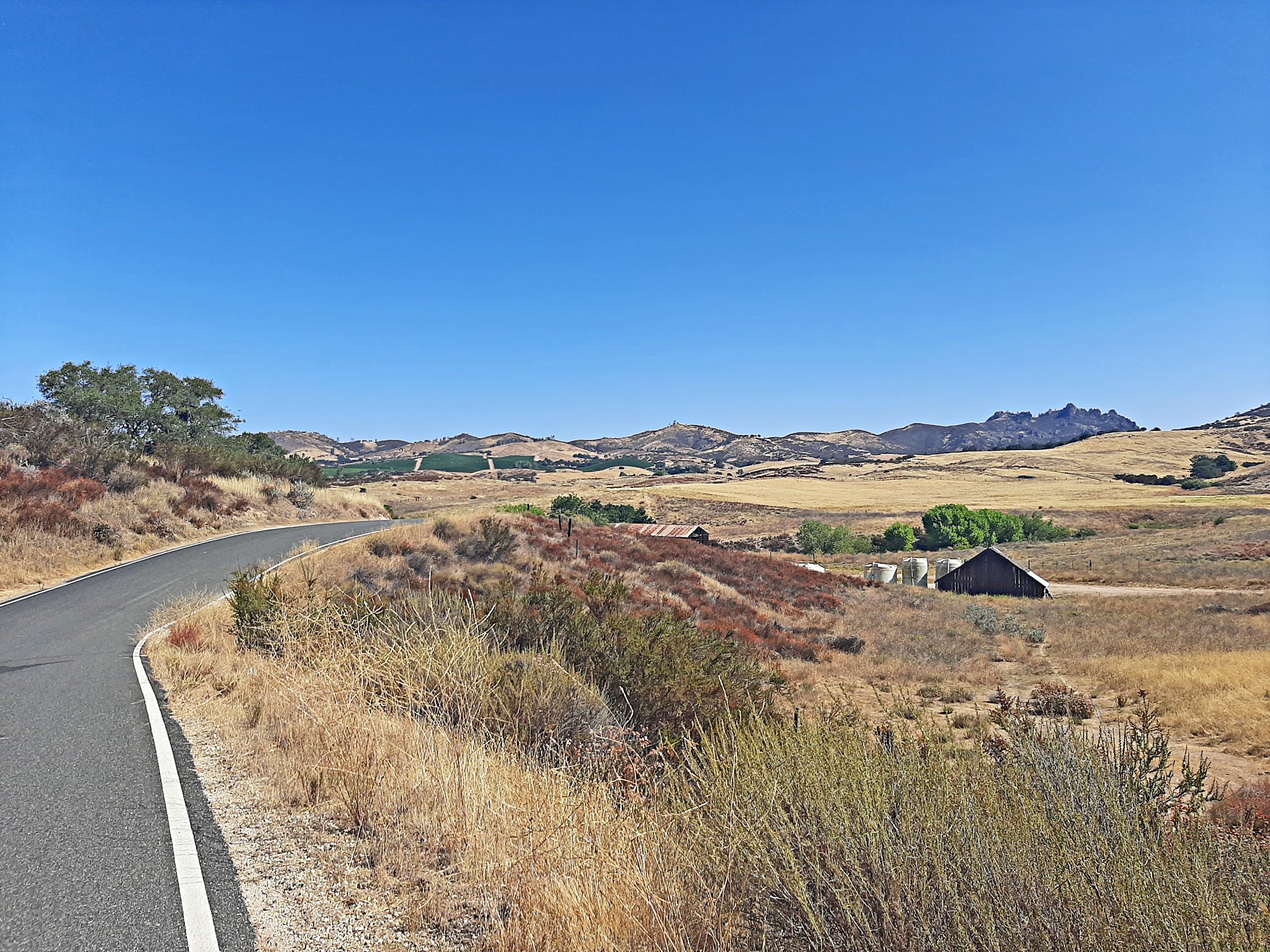 Cycling Pinnacles National Park, California - one-lane road winding through land covered in brown grasses, Pinnacles seen in the distance