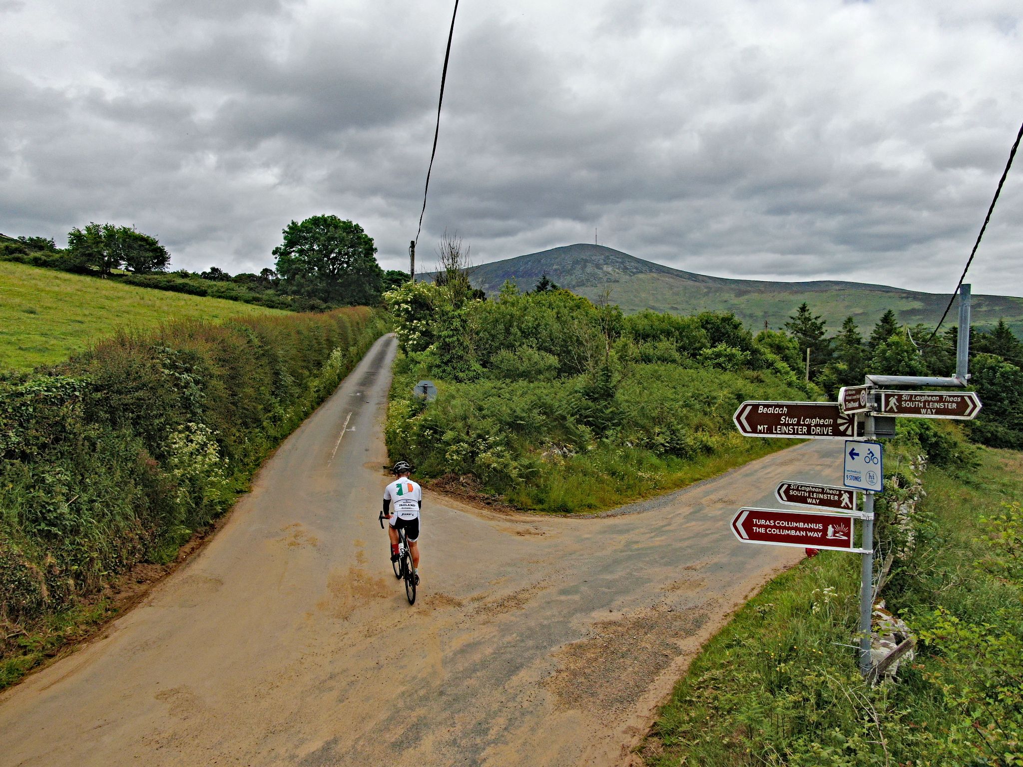 PJAMM Cyclist rides at fork in road, sharp right turn onto Mt. Leinster Drive