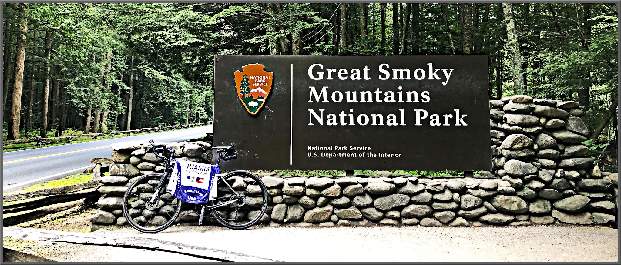Cycling Great Smoky Mountains National Park, Tennessee - bike with blue and white PJAMM Cycling jersey draped over it leaning against NPS sign for Great Smoky Mountains National Park