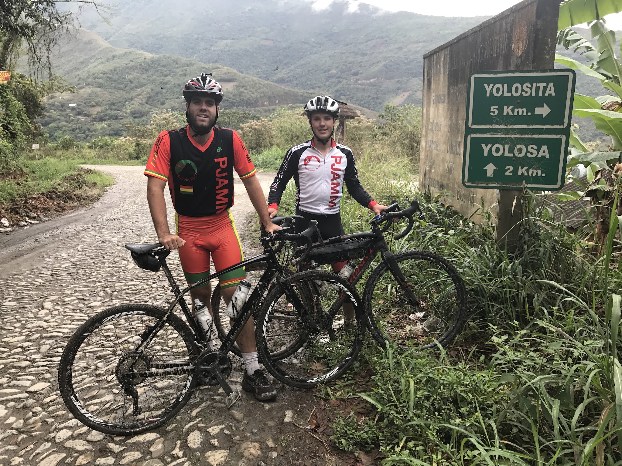 2 cyclists with bikes stopped at sign on Yungas Road
