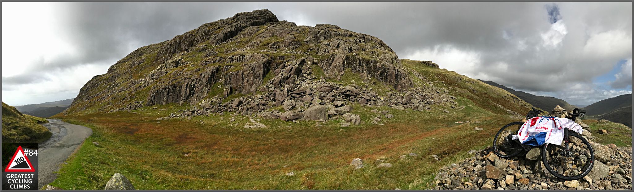 panoramic photo shows bike parked on rocks next to roadside, rocky hillside 
