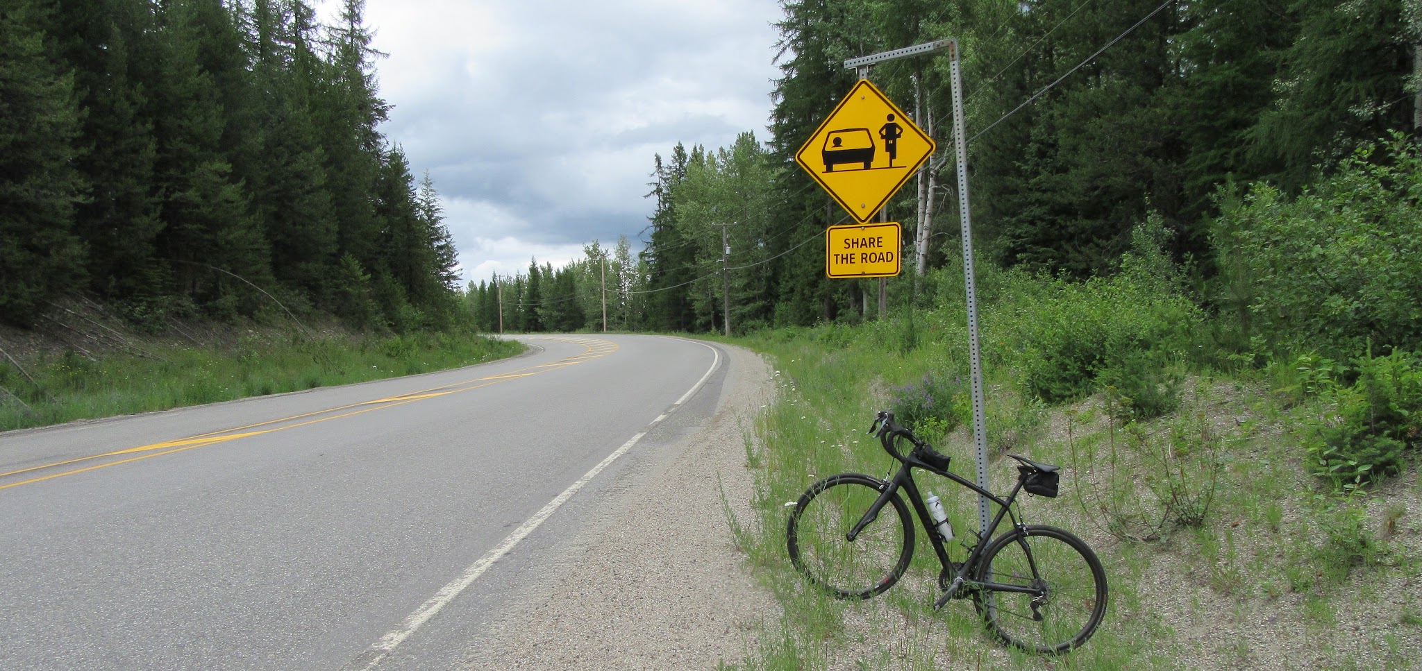 Cycling Strawberry Pass, BC, CAN - road, bike leaning against share the road sign.