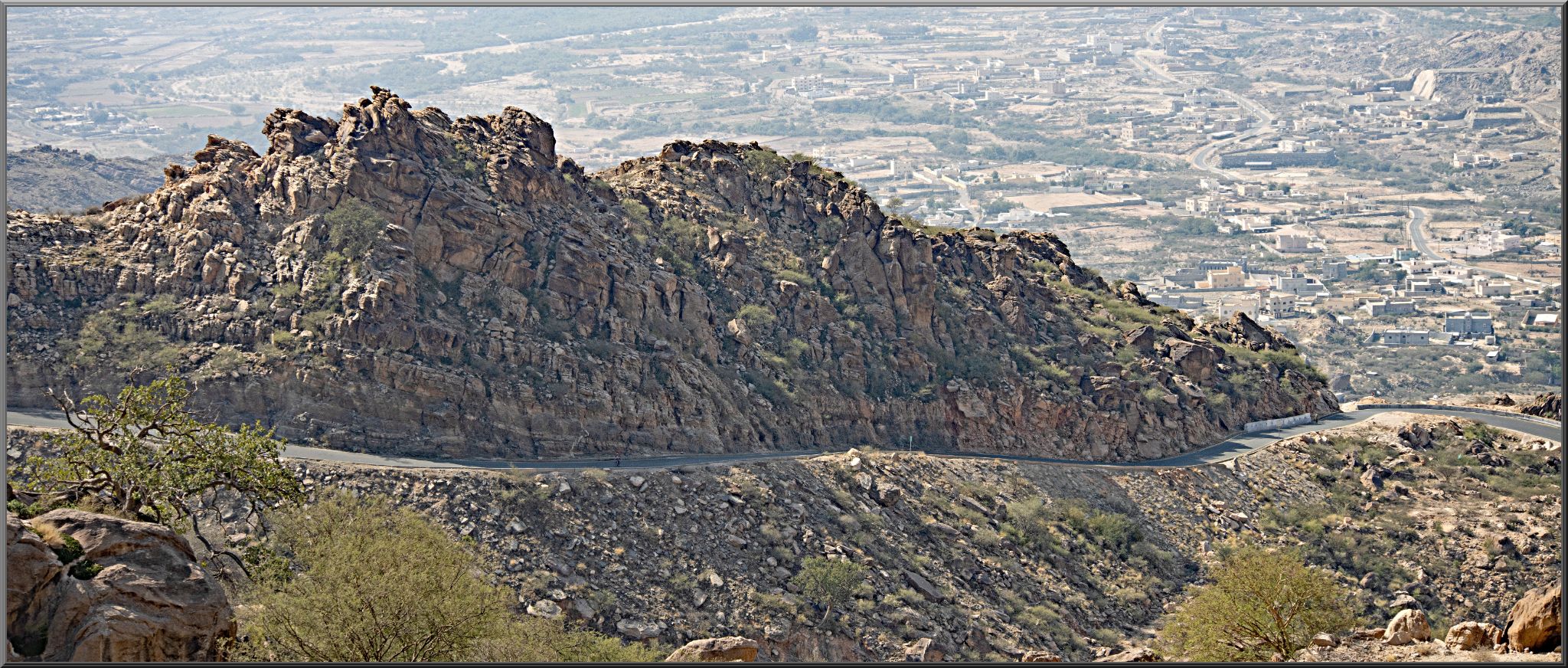Cycling Parmah Pass, Saudi Arabia - panoramic view looking down at road carved into rocky mountainside below