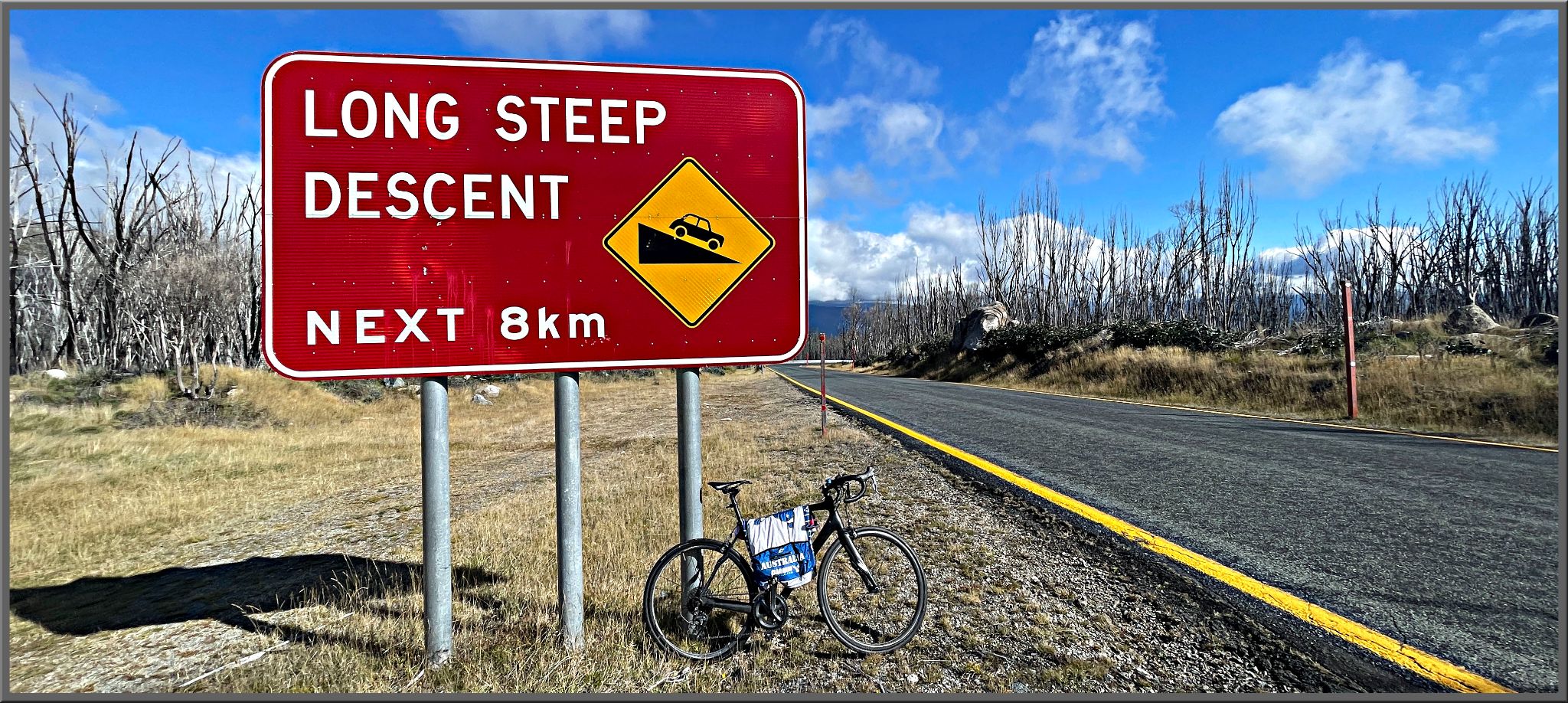 bike parked next to road sign reading "Long Steep Descent Next 8km"