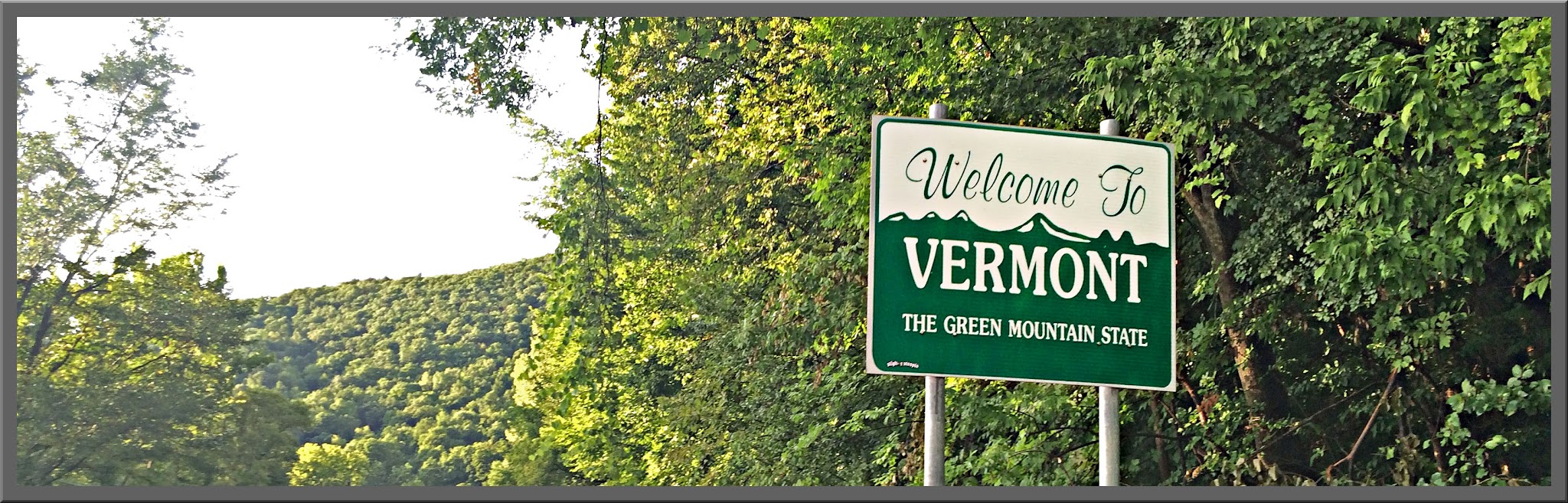 Cycling Mt. Ascutney, Vermont - road sign reads "Welcome To Vermont, the Green Mountain State", surrounded by dense green folliage